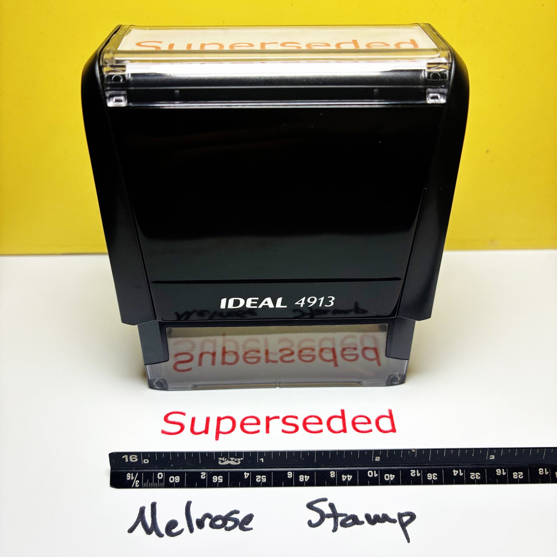 Rubber stamp with 'Superseded' text on a yellow and white background, accompanied by a ruler for scale.