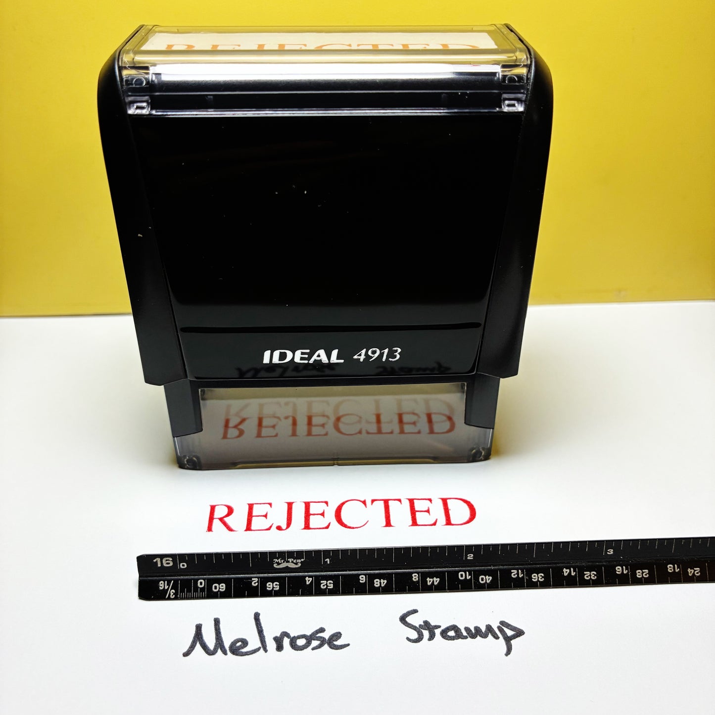 Black stamp with 'REJECTED' text  rubber stamp red ink on white paper with a yellow background