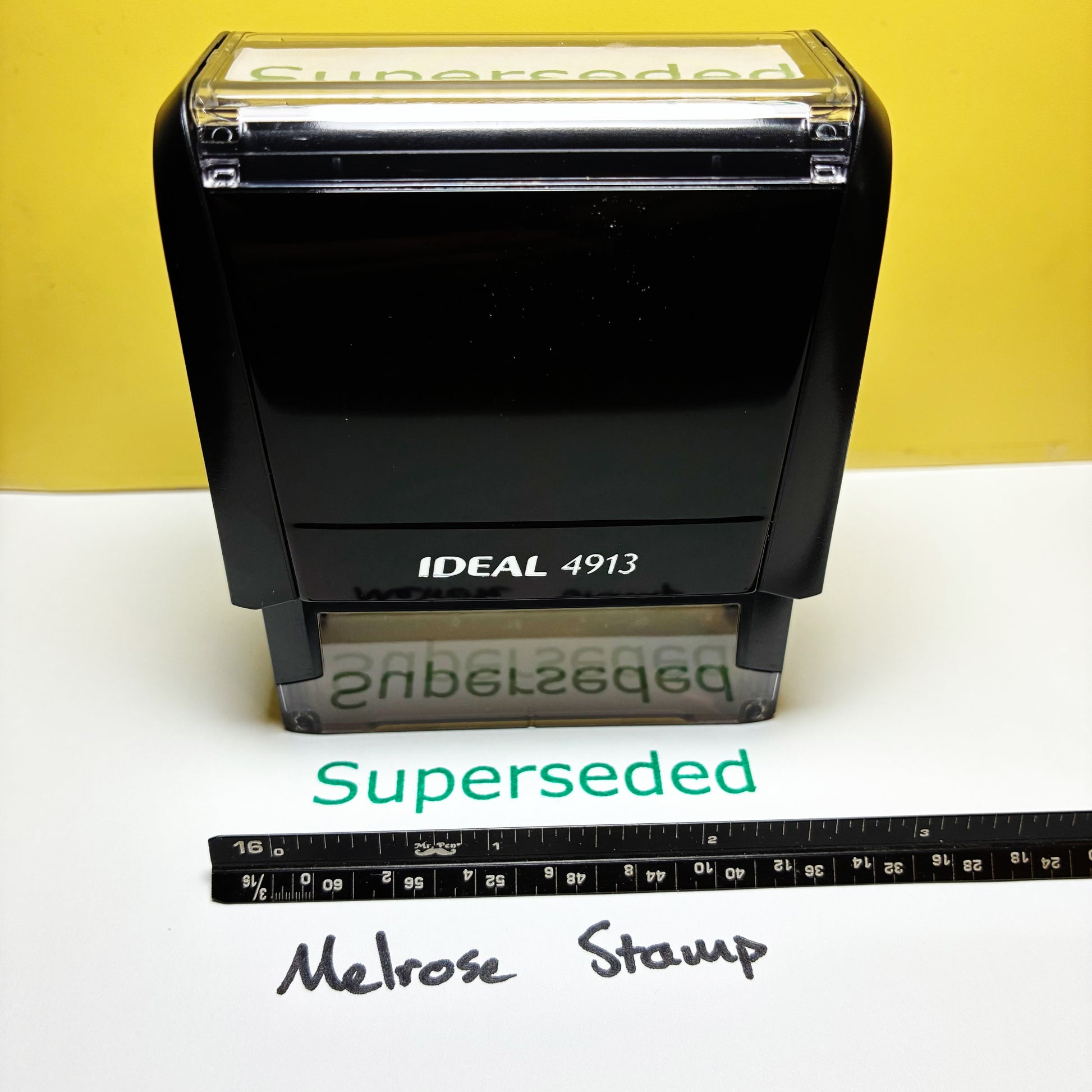 Black stamp with 'Superseded' text on a white surface with a yellow background rubber stamp green ink