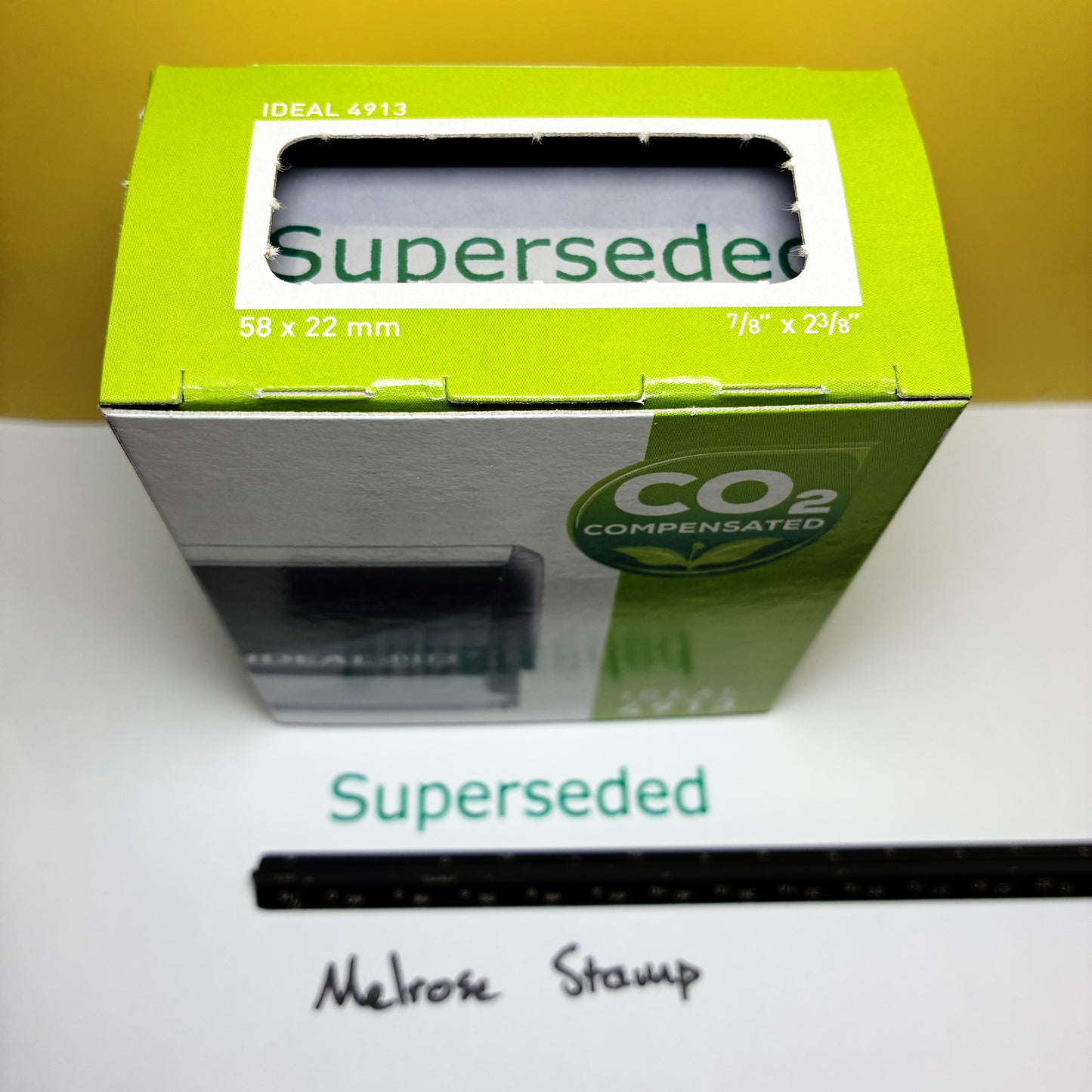 Green box labeled 'Superseded' rubber stamp green ink with a ruler on a white paper