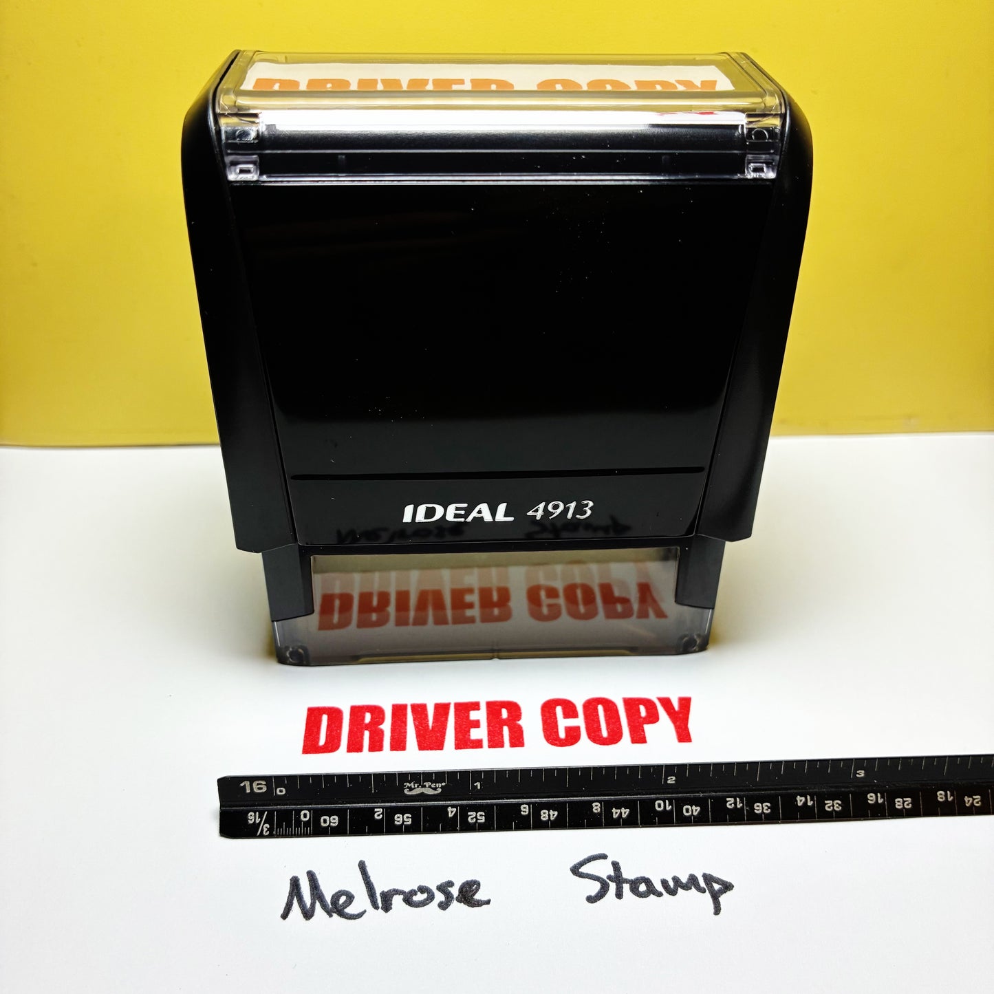 Black stamp with 'IDEAL 4913' and 'DRIVER COPY' text, next to a ruler on a white surface with yellow background rubber stamp red ink