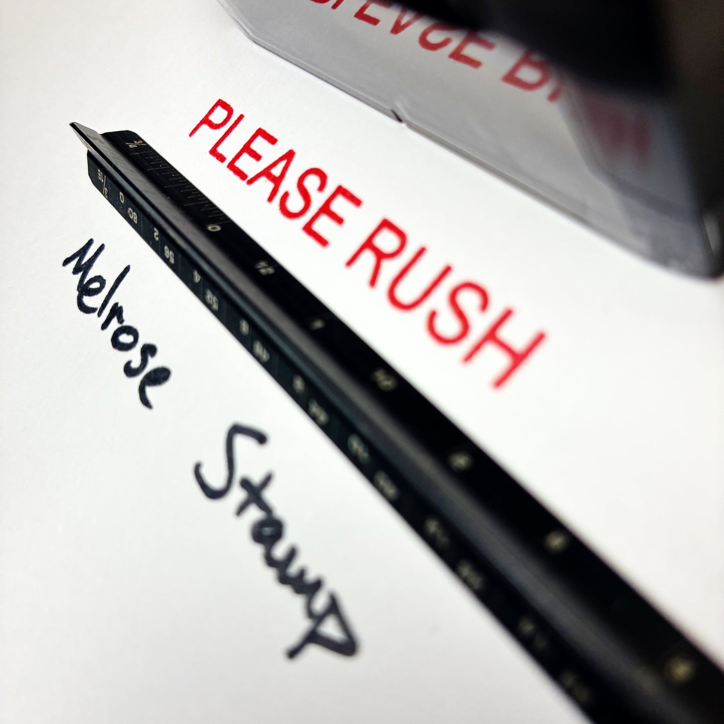 Document with 'PLEASE RUSH' text and a pen on a white background rubber stamp red ink