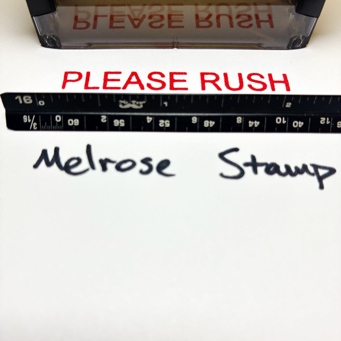 Stamp with 'PLEASE RUSH' text and a ruler below, on a white background.