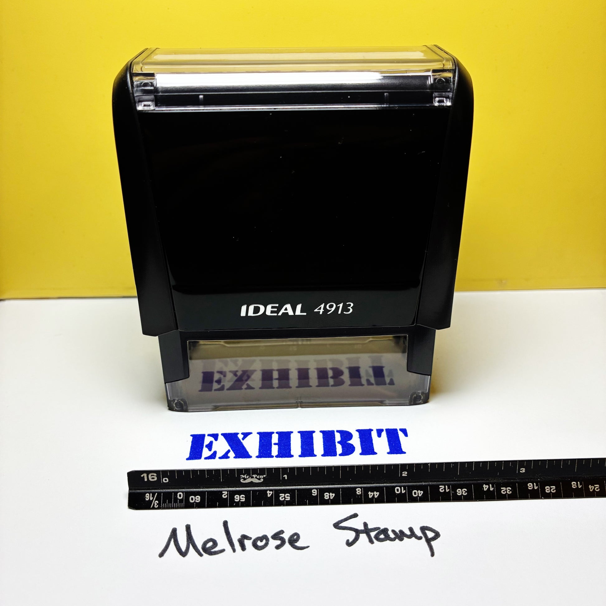 Black stamp with 'EXHIBIT' text blue ink on a white surface against a yellow background