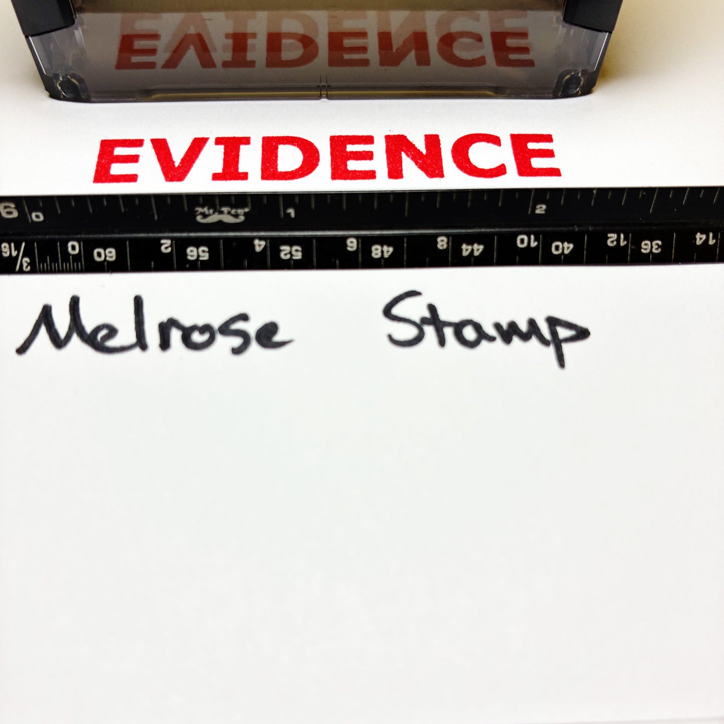 Red 'EVIDENCE' stamp on white paper with a ruler and 'Melrose Stamp' text.