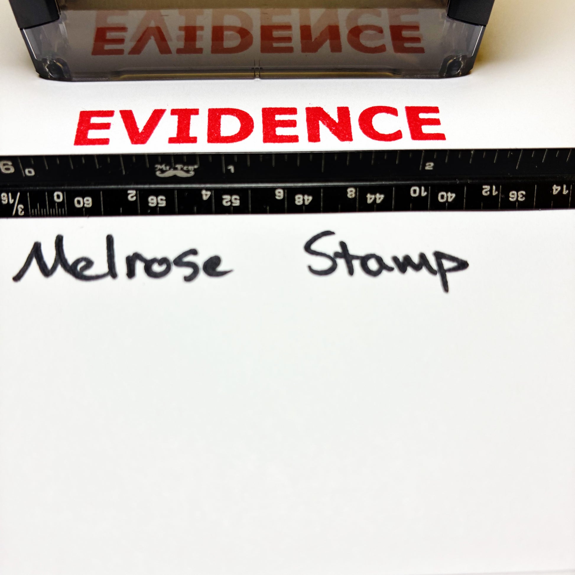 Red 'EVIDENCE' stamp on white paper with a ruler and 'Melrose Stamp' text.