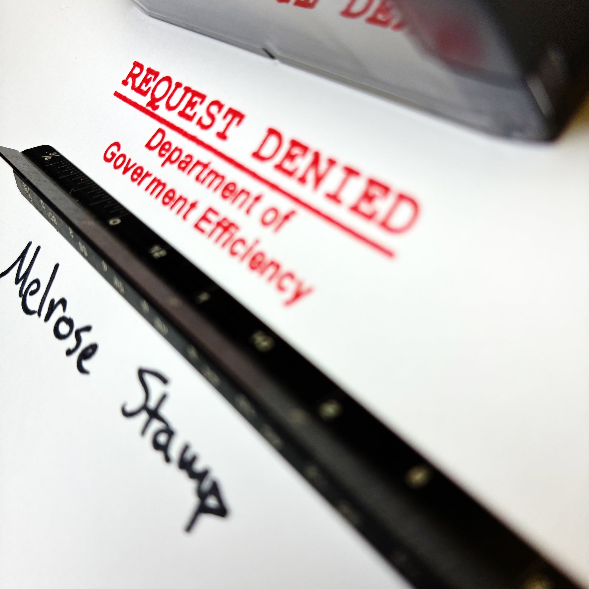 Close-up of a document with 'REQUEST DENIED' stamp and 'Melrose Stamp' text.