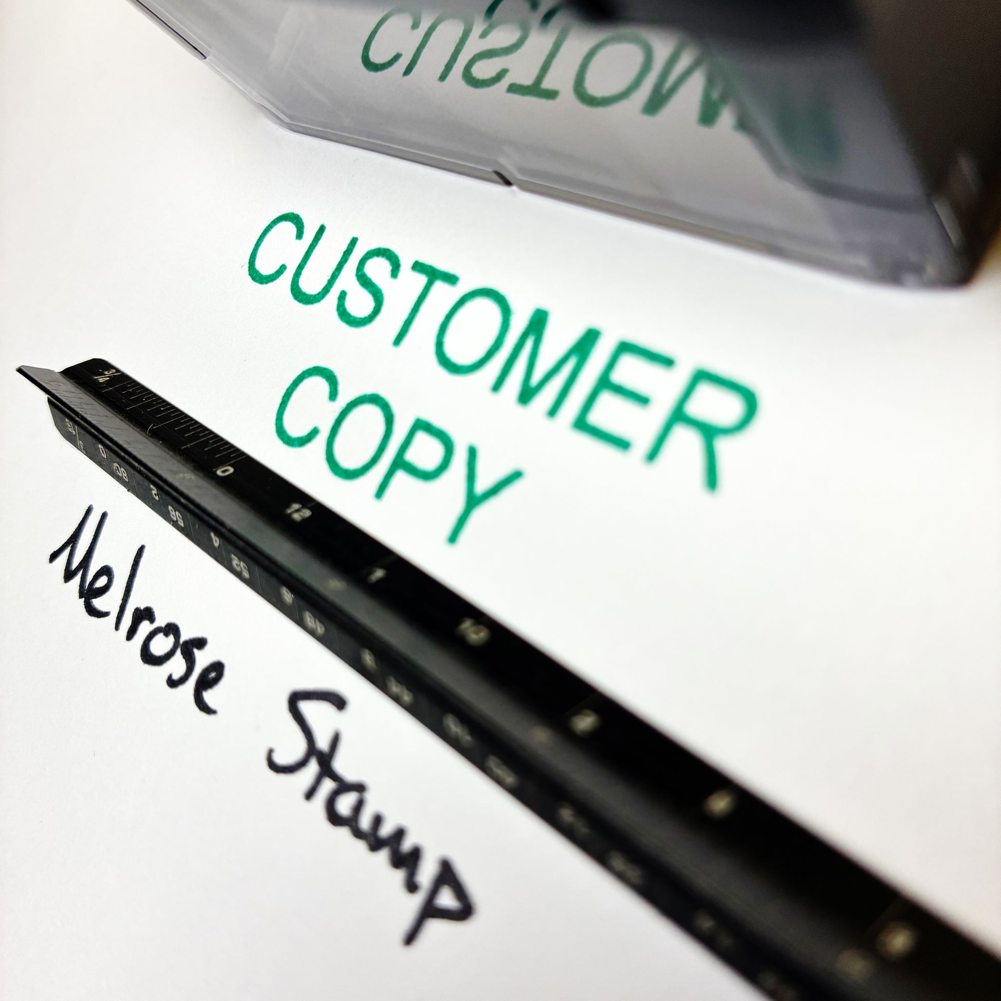 Close-up of a stamp with 'CUSTOMER COPY' and 'Melrose Stamp' text on a white background.