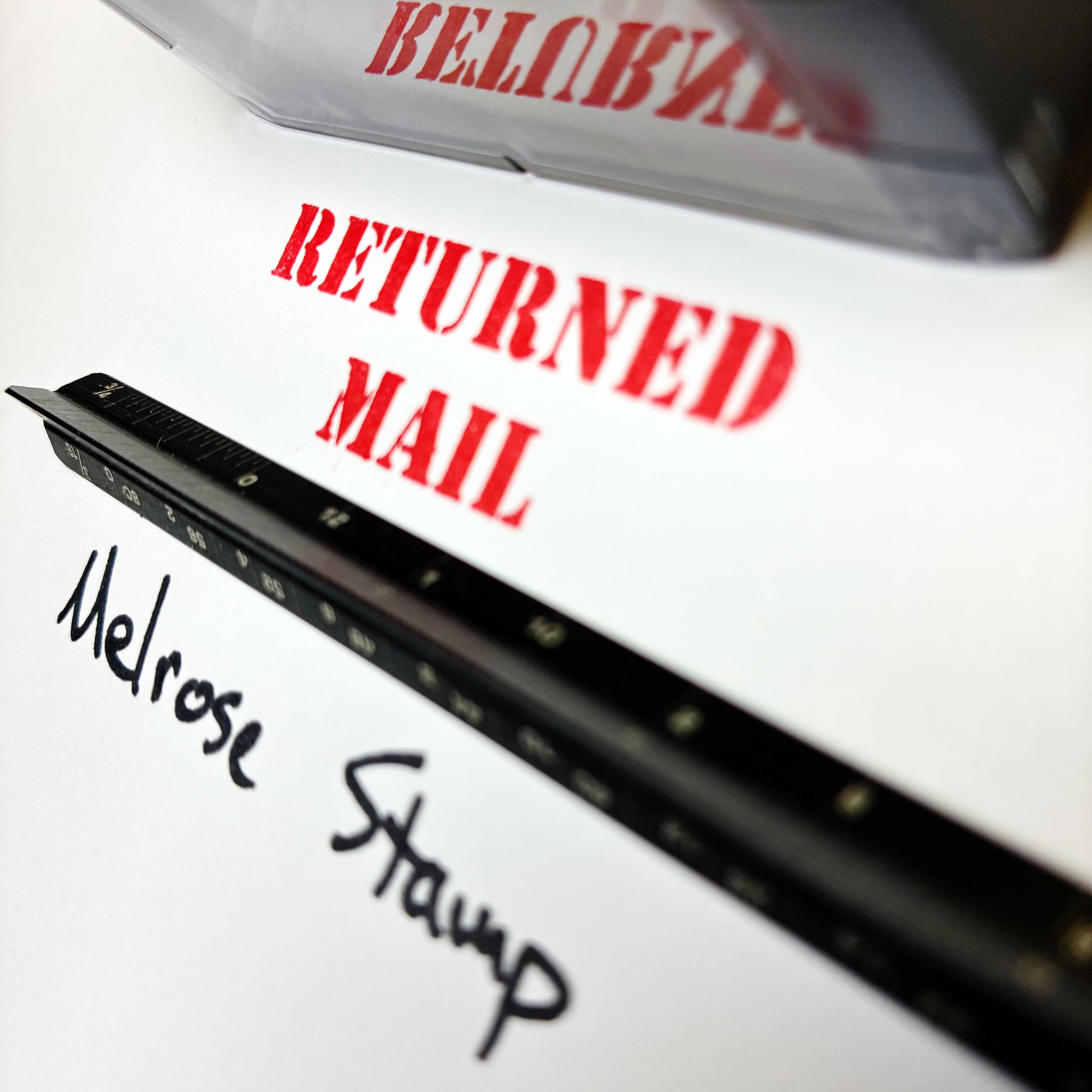 Close-up of 'RETURNED MAIL' rubber stamp and 'Melrose Stamp' text.