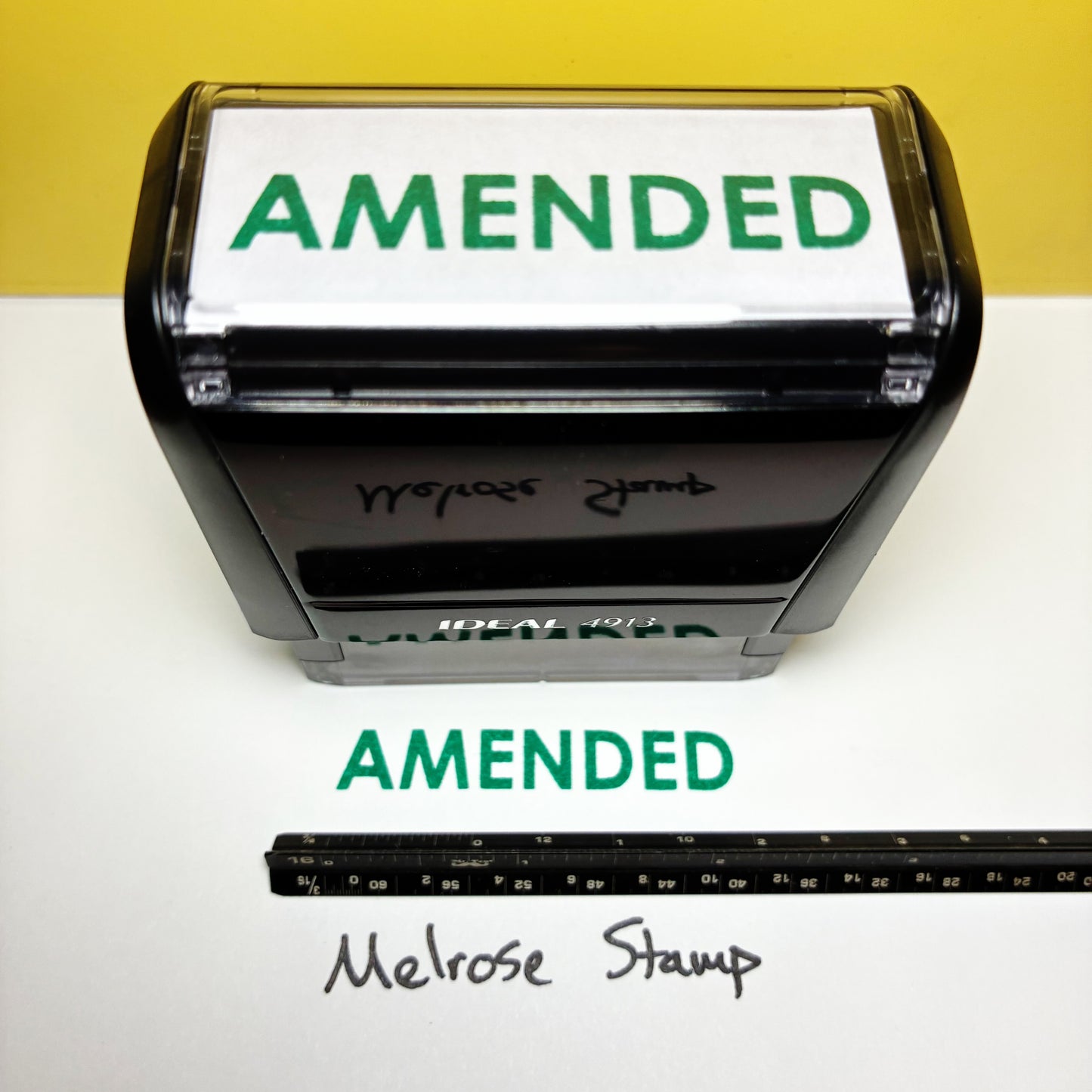 Self-inking rubber stamp with 'AMENDED' green ink on a white background