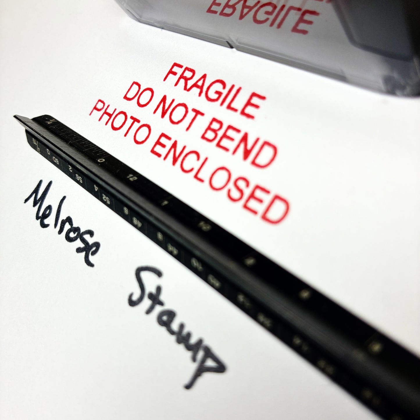 Close-up of a package with 'Fragile Do Not Bend Photo Enclosed' text and 'Melrose Stump' branding.
