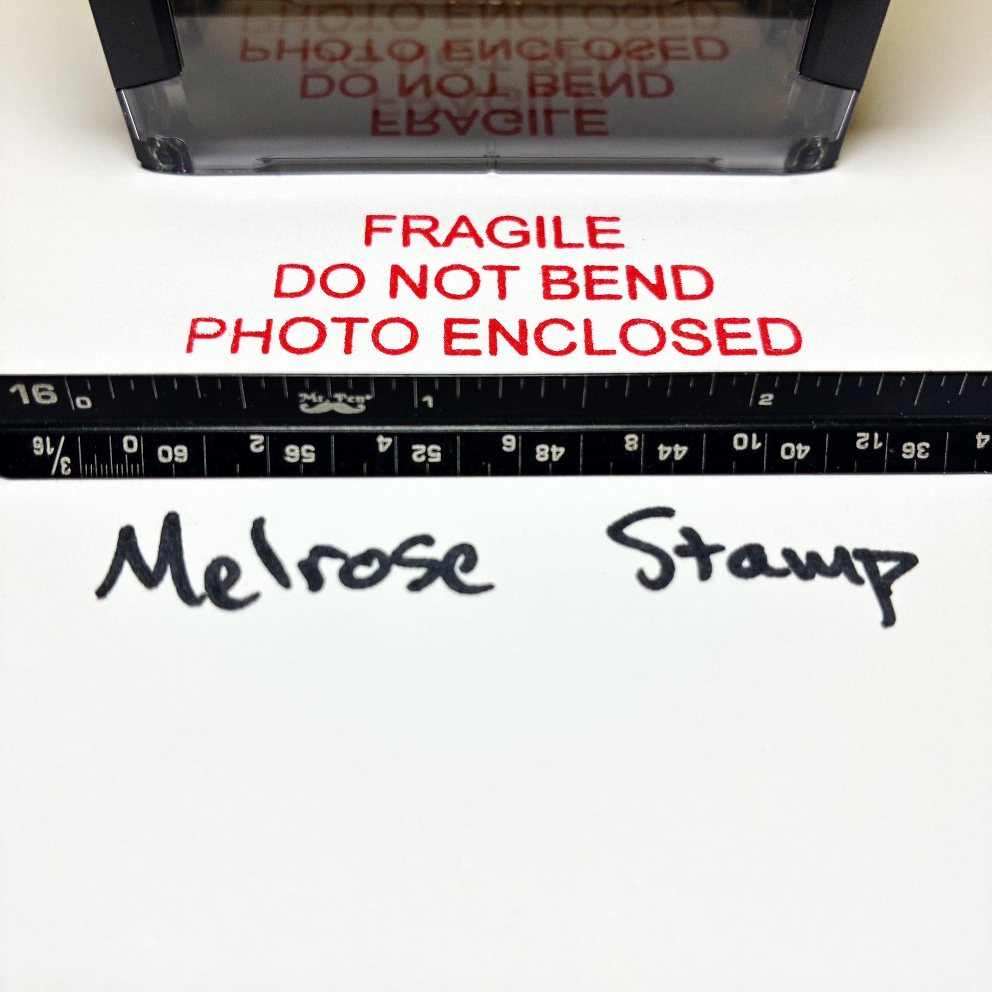 Rubber Stamp with text 'FRAGILE DO NOT BEND PHOTO ENCLOSED' and a ruler for scale on a white background.