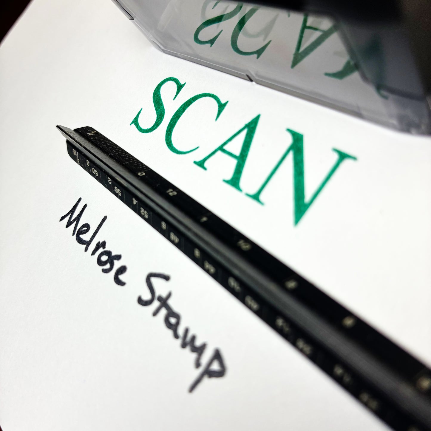 Black ink stamp with 'Melrose Stamp' text on a white background, next to green text 'SCAN'.