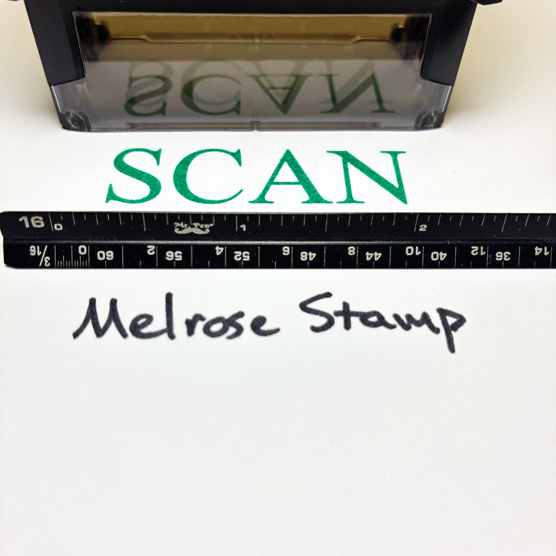 Stamp with 'SCAN' text green ink and a ruler below, on a white background