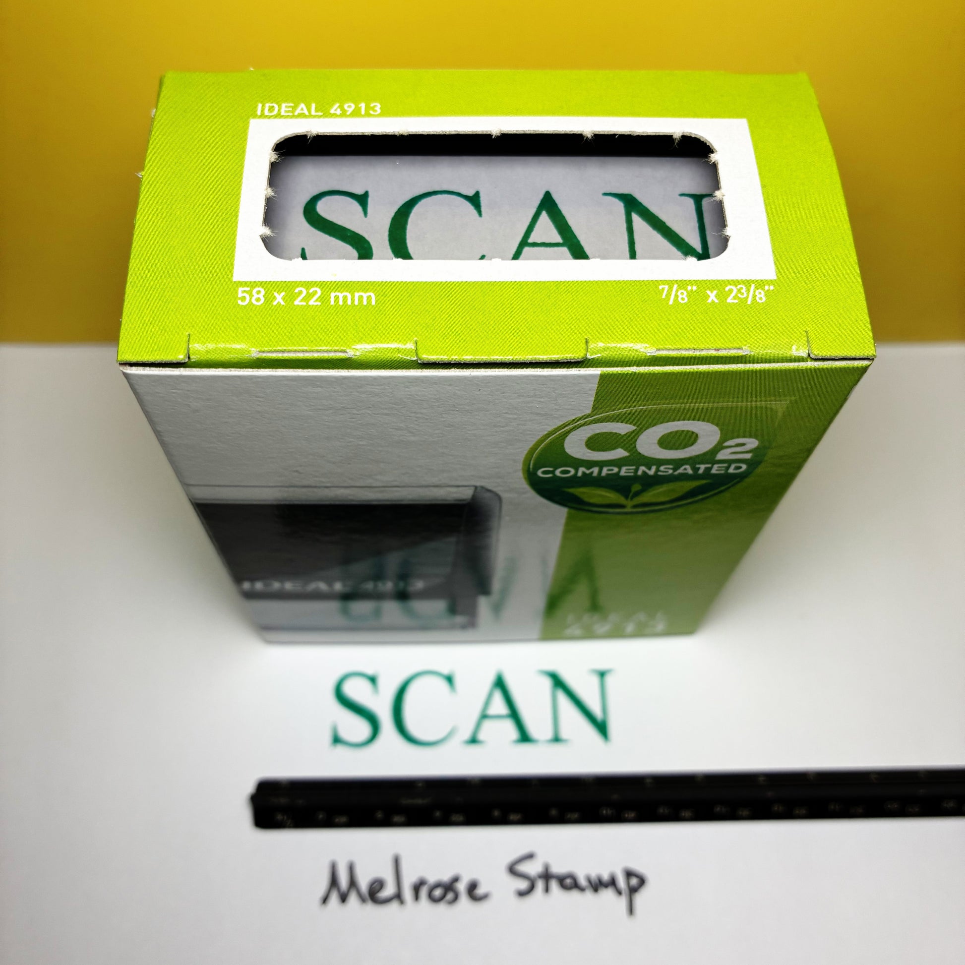 Green box labeled 'SCAN' with a rubber stamp on a white surface.