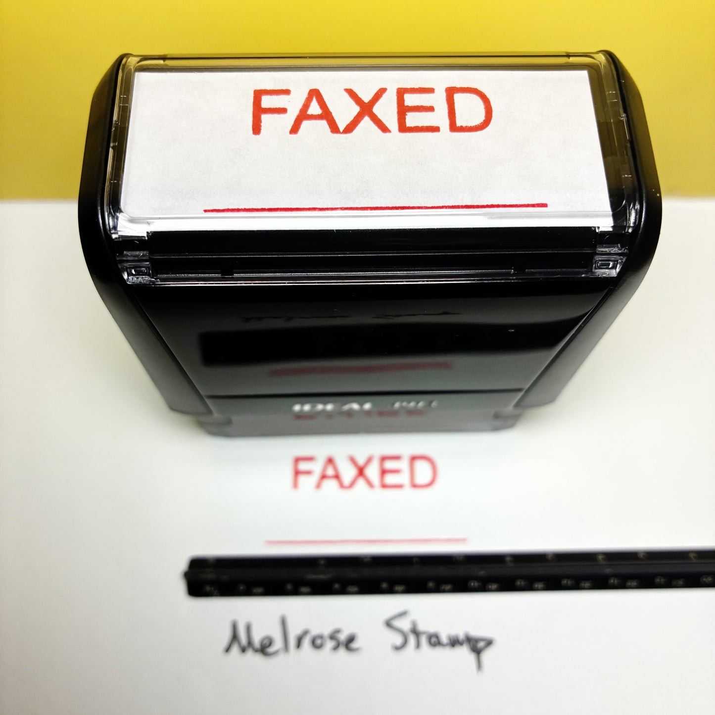 Stamp with 'FAXED' text on a white surface with a yellow background