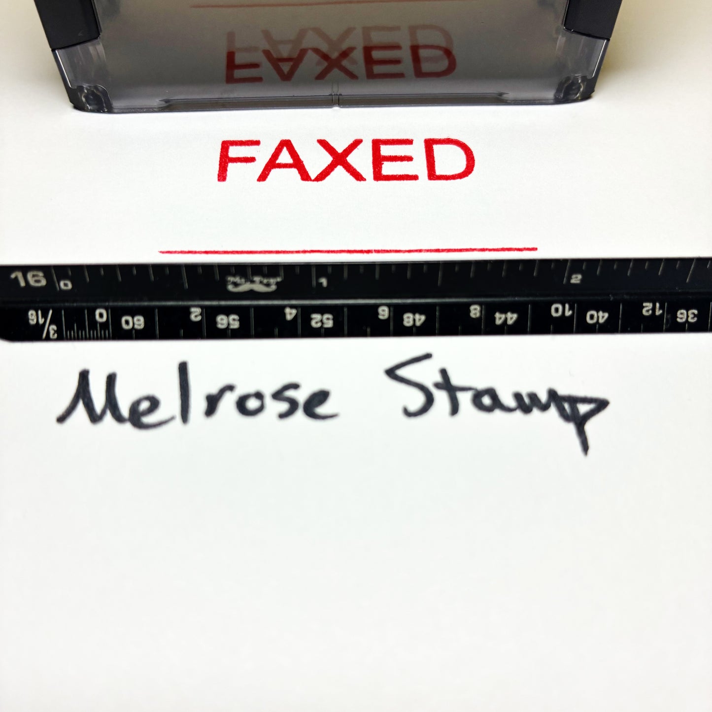 Red 'FAXED' stamp on paper with a ruler and 'Melrose Stamp' branding.