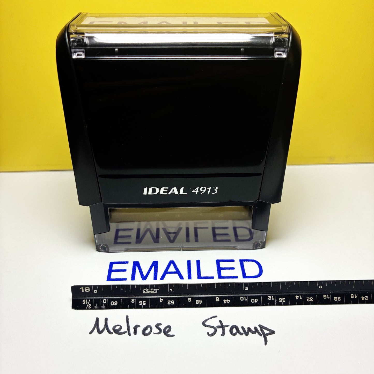 Rubber Stamp Ideal 4913 stamp with 'EMAILED' text blue ink and a ruler for scale on a white background.
