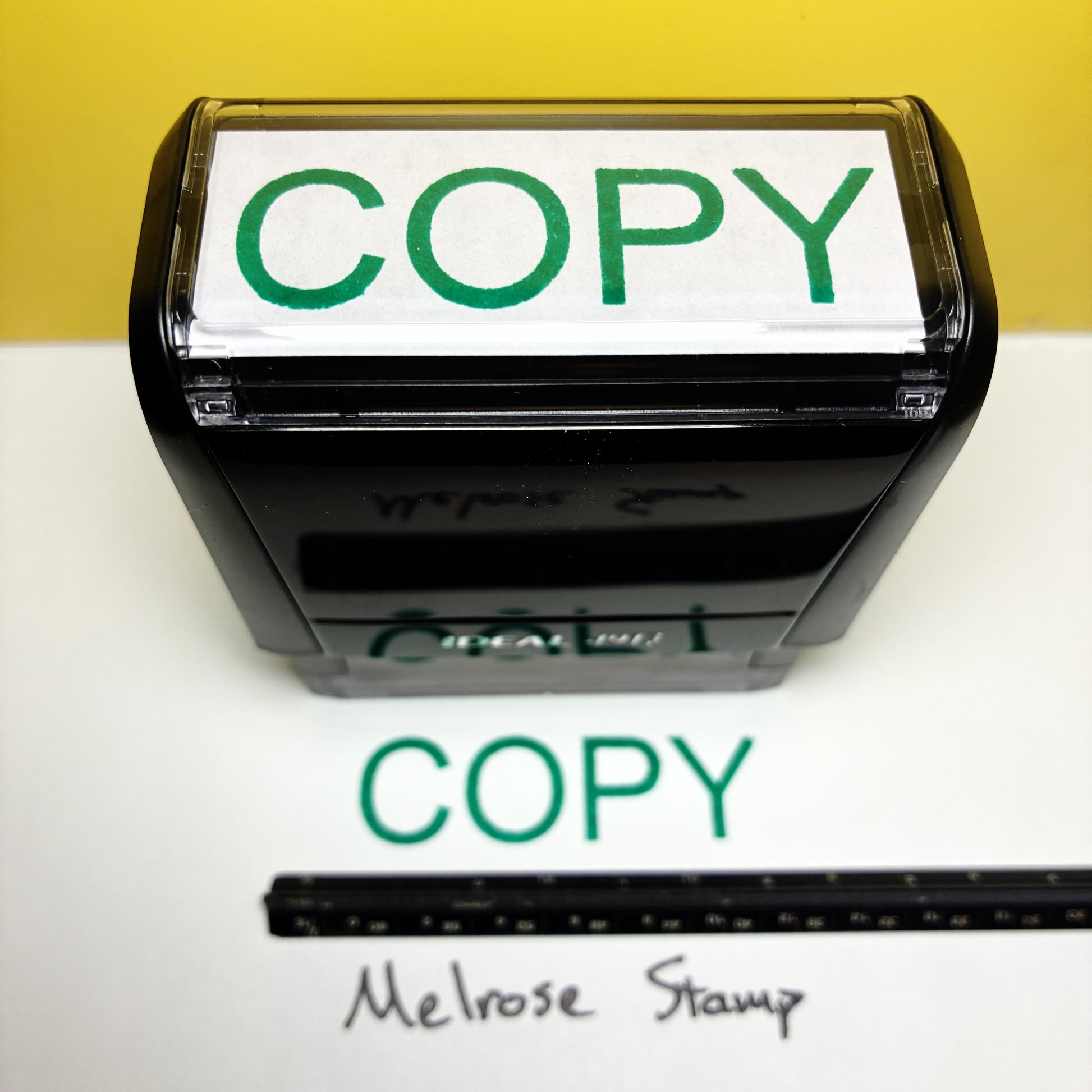 Rubber stamp with 'COPY' text green ink on a white surface with a yellow background