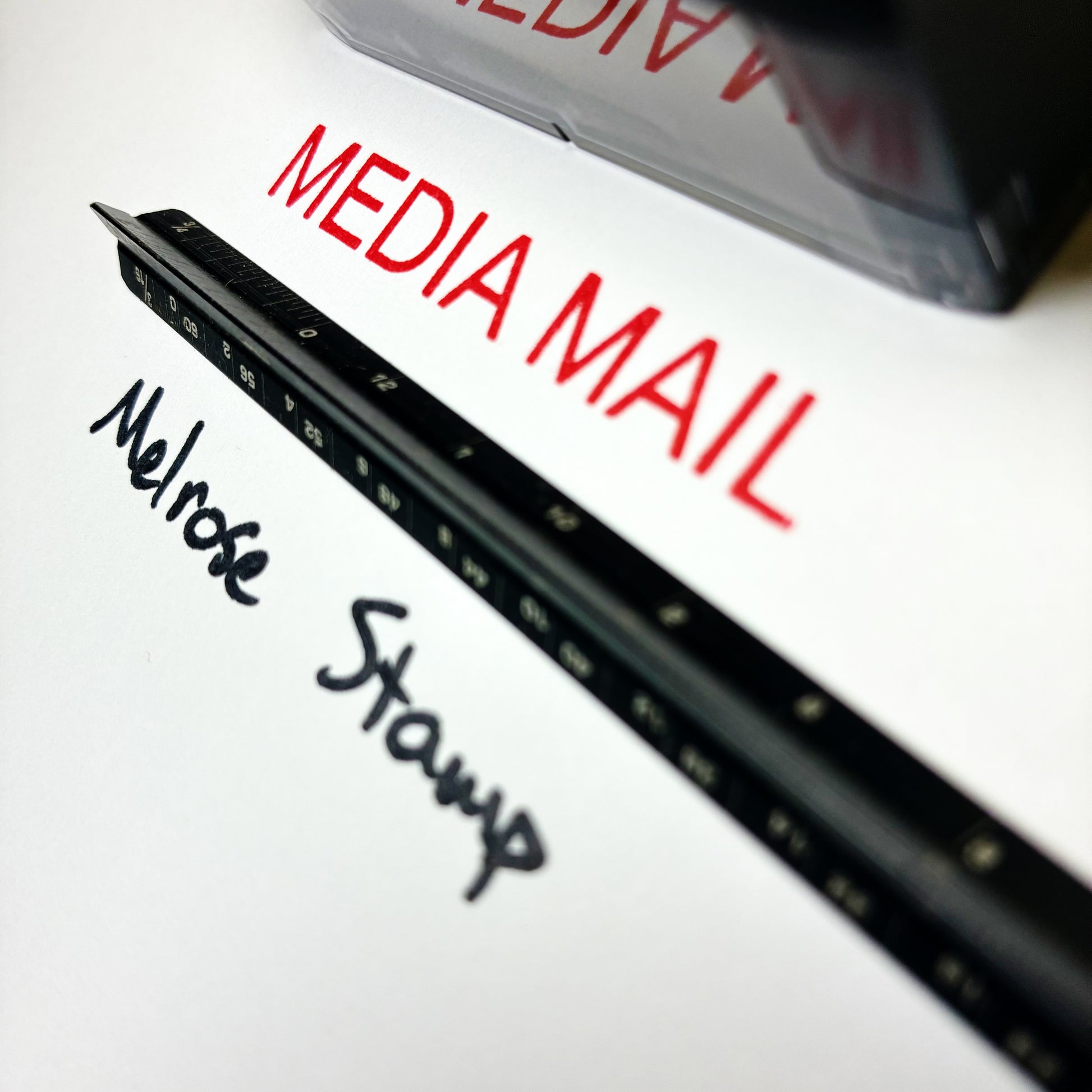 Rubber stamp with 'Melrose Stamp' and 'Media Mail' text  red ink large close up