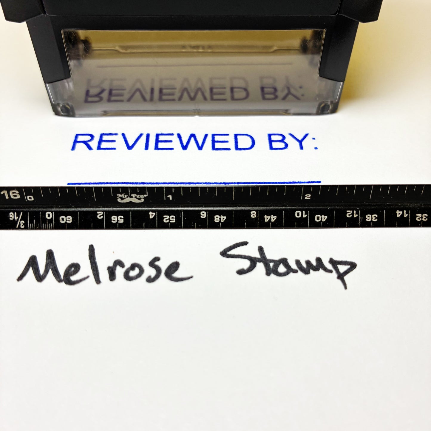 Rubber stamp with 'REVIEWED BY:' text and a ruler below, on a white background.