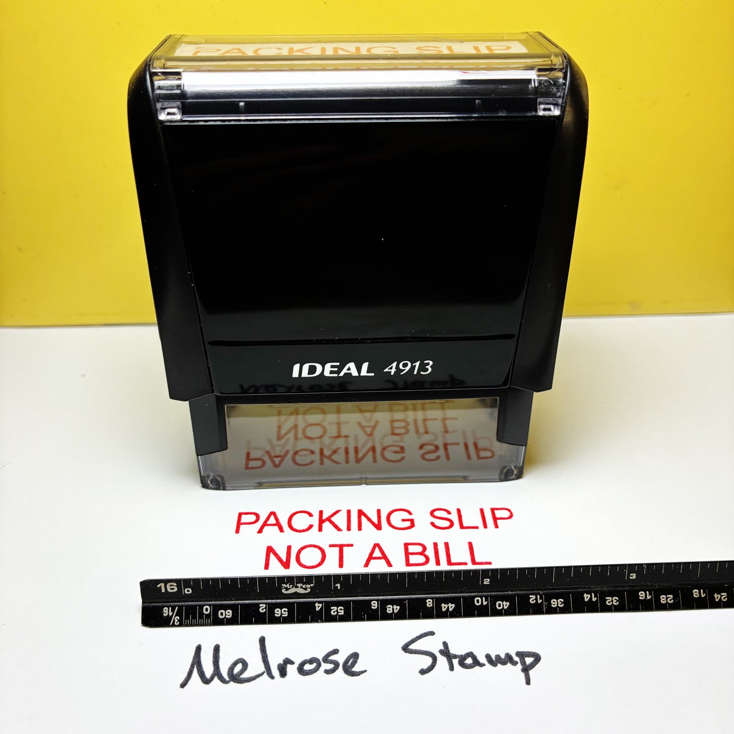 Rubber stamp with 'Packing Slip Not a Bill' text on a white surface with a yellow background