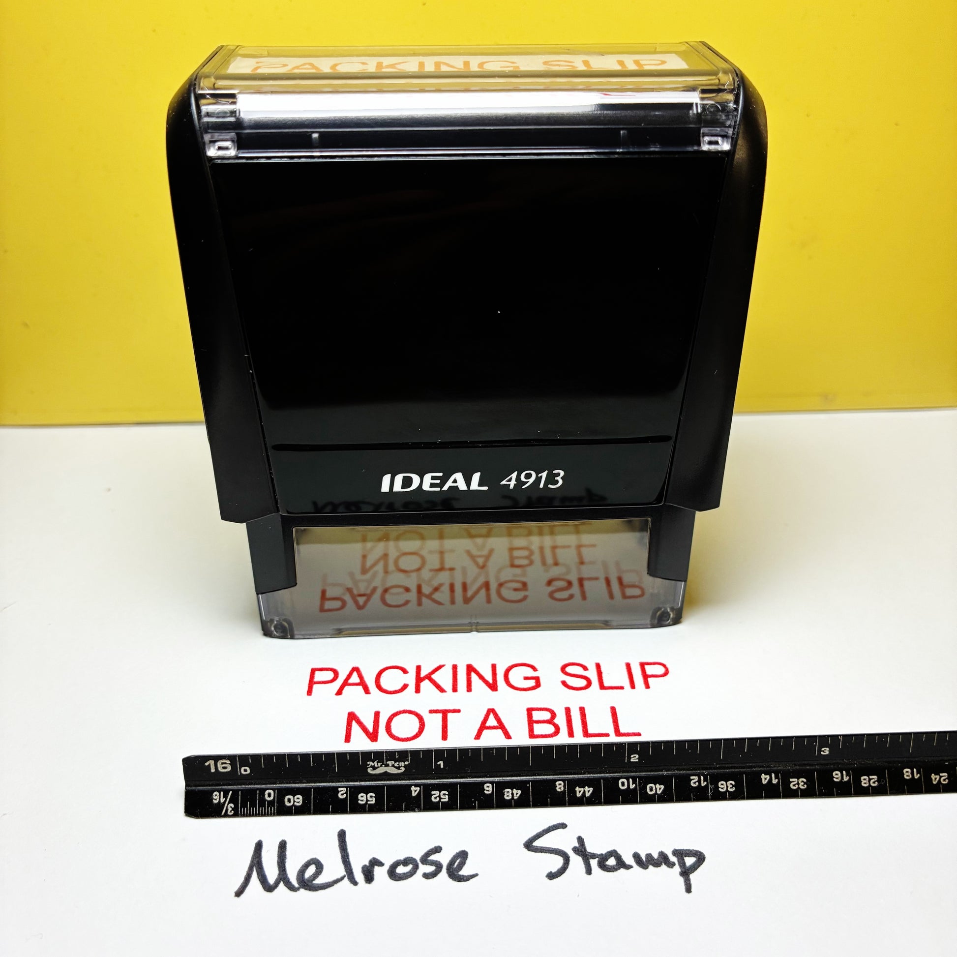 Rubber stamp with 'Packing Slip Not a Bill' text on a white surface with a yellow background