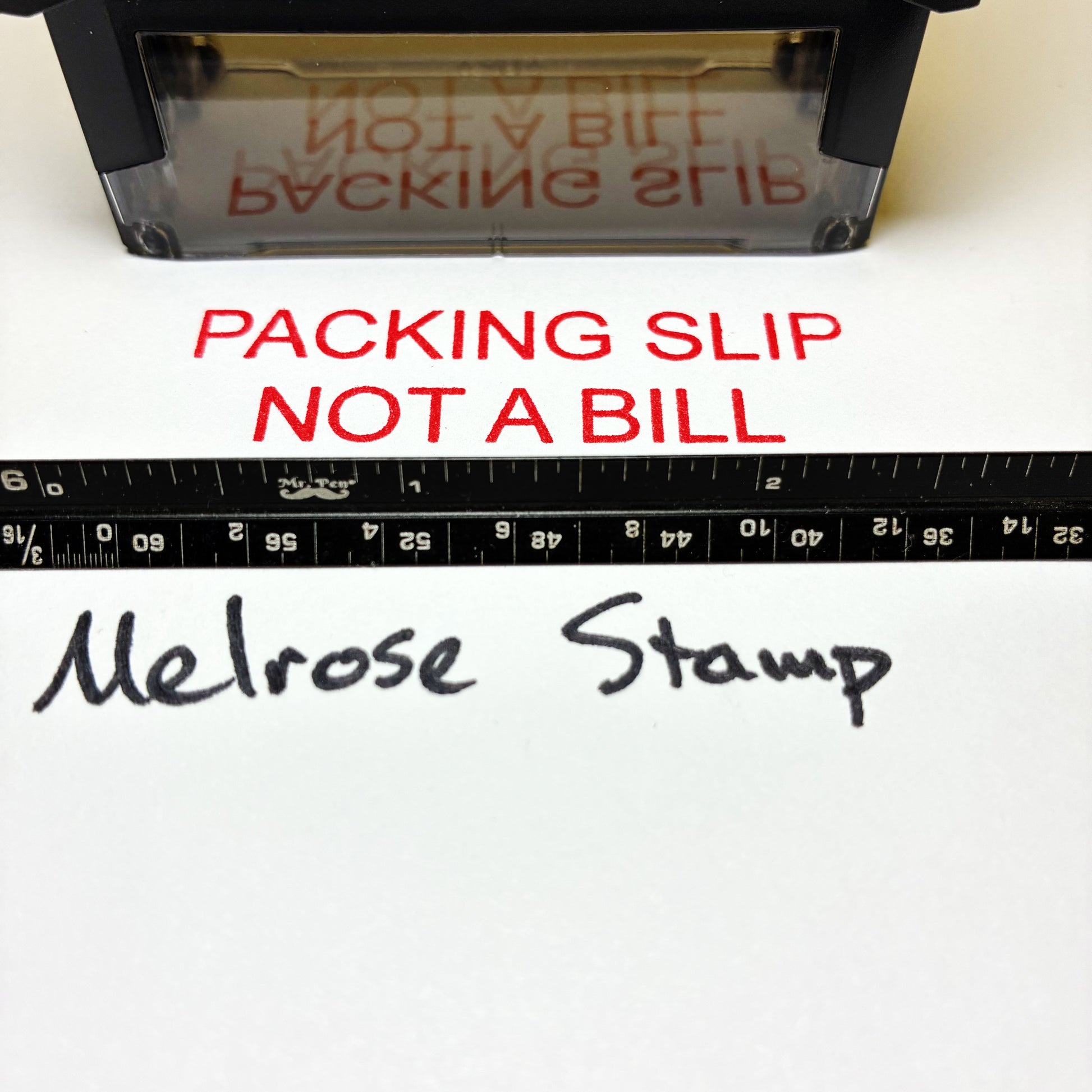 Stamp with text 'Packing slip not a bill' and a ruler below on a white background