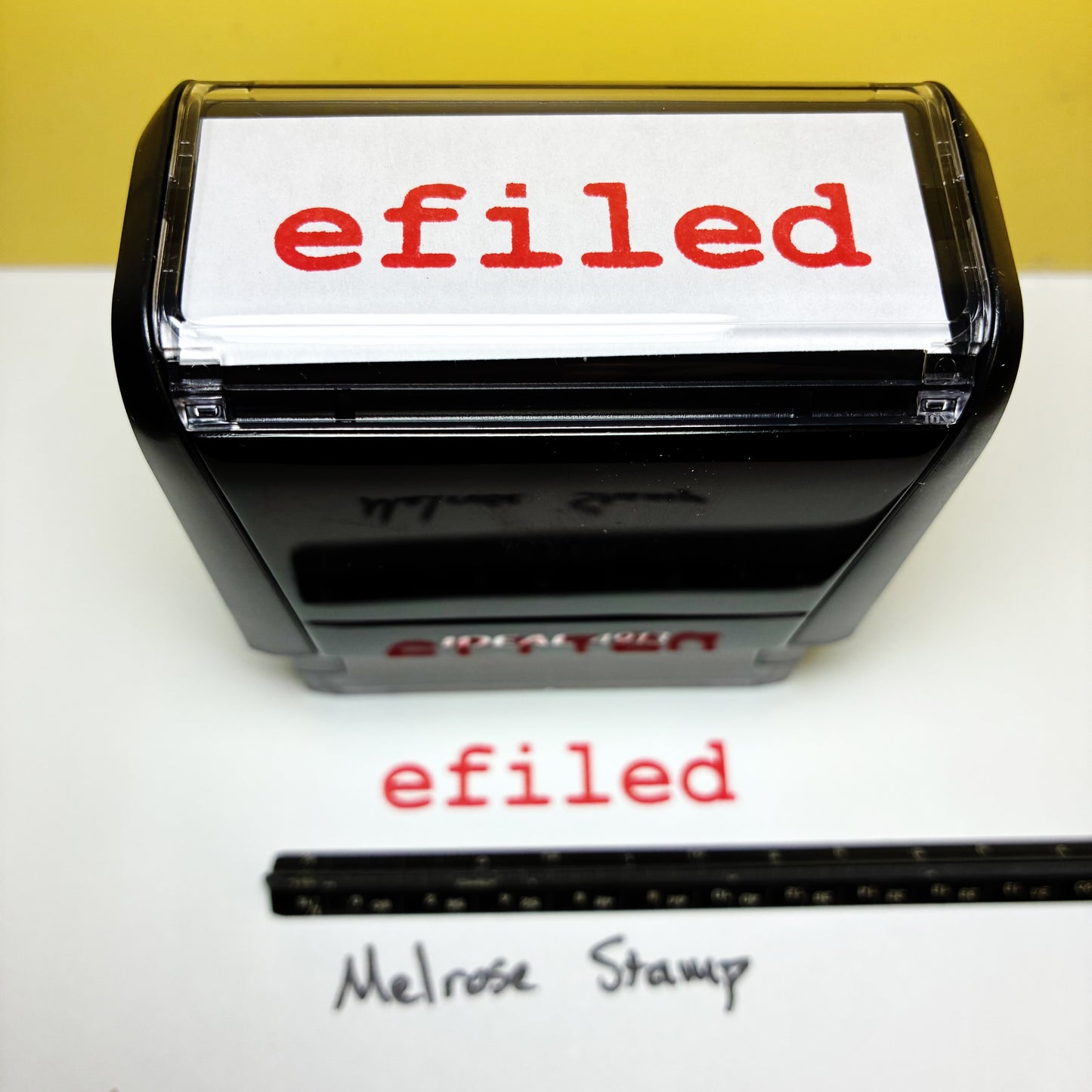 Rubber stamp with 'efiled' text on a white background, next to a ruler for scale.