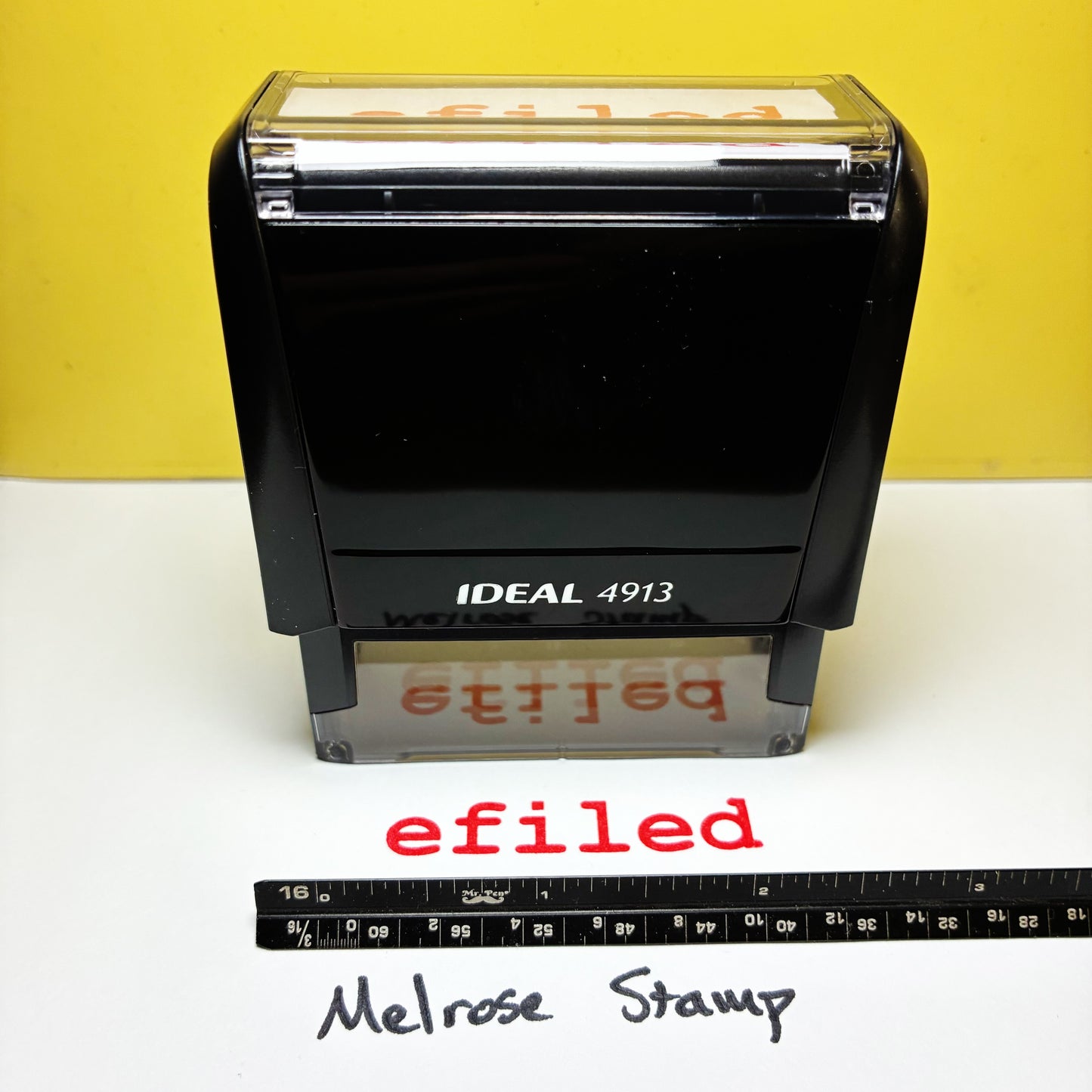 Rubber stamp with 'efiled' text red ink on a white surface and yellow background