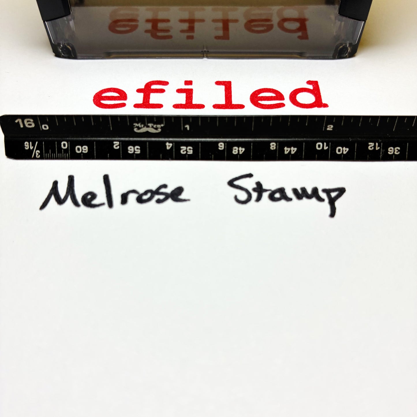 Text 'efiled' printed on a white background with a ruler and stamp visible.
