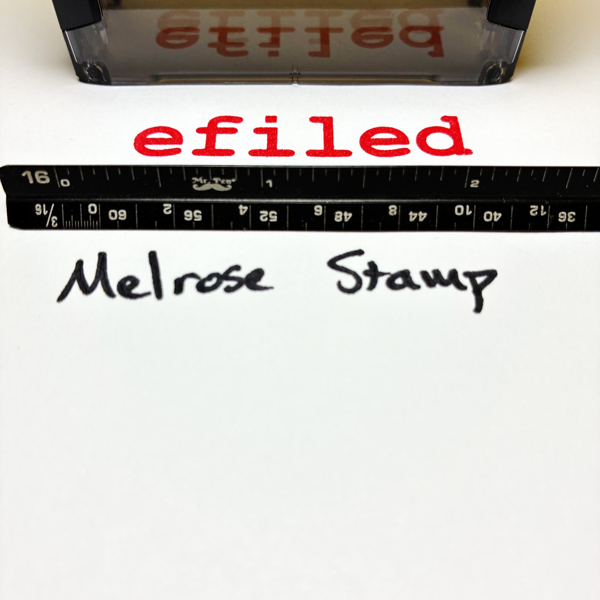 Text 'efiled' printed on a white background with a ruler and stamp visible.