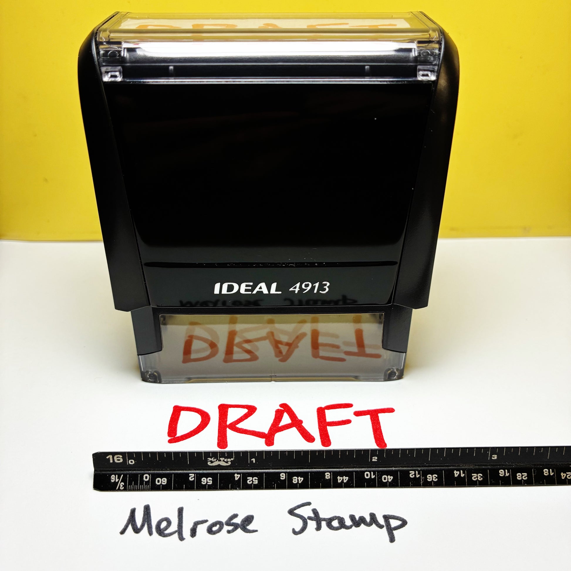 Rubber stamp with 'DRAFT' text red ink on a white surface with yellow background