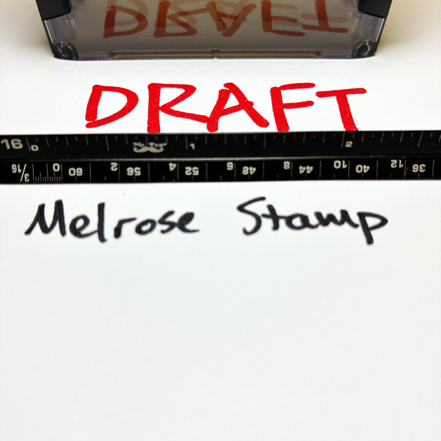 Red 'DRAFT' text on paper with a ruler and 'Melrose Stamp' branding.