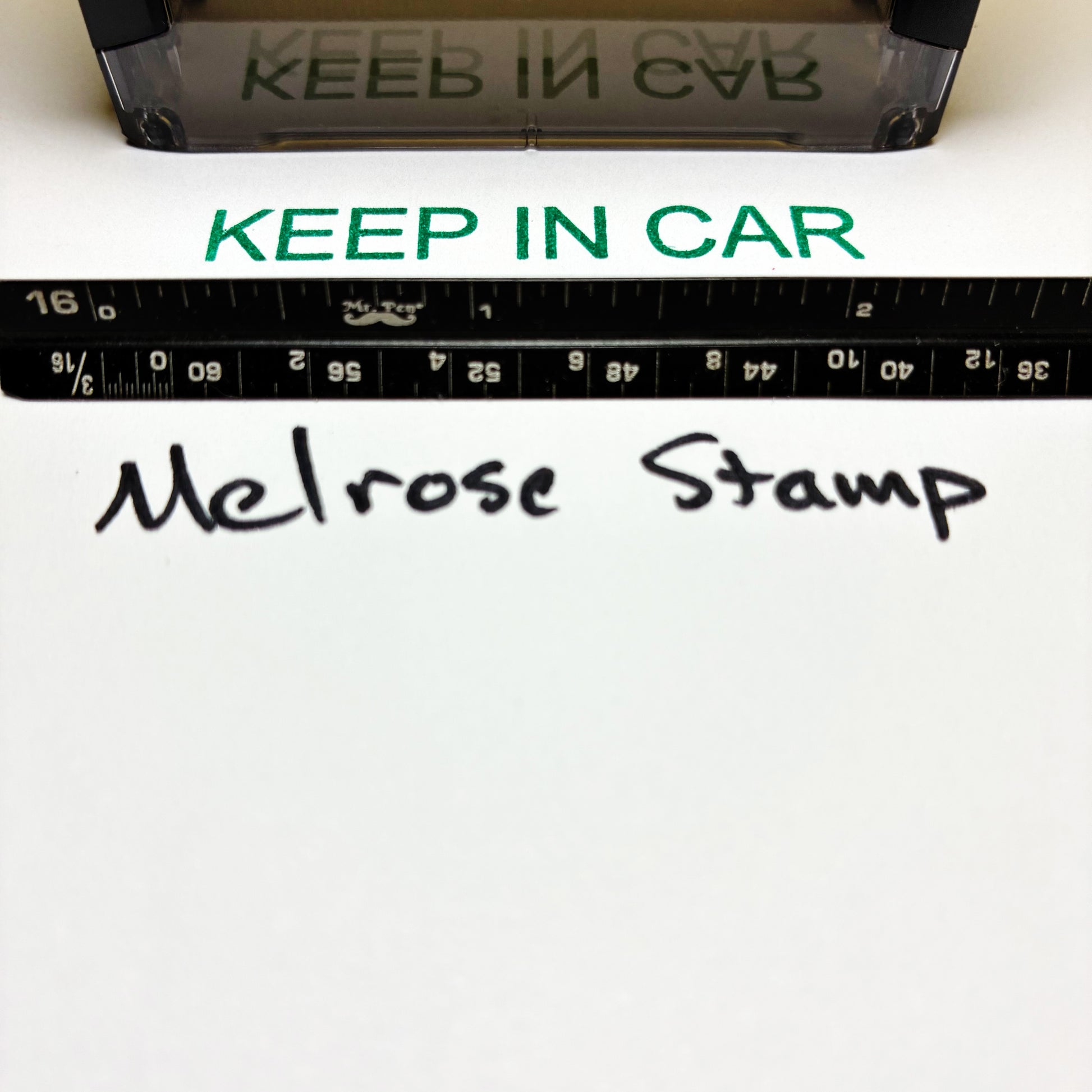 Stamp with 'KEEP IN CAR' text and a ruler below it on a white background