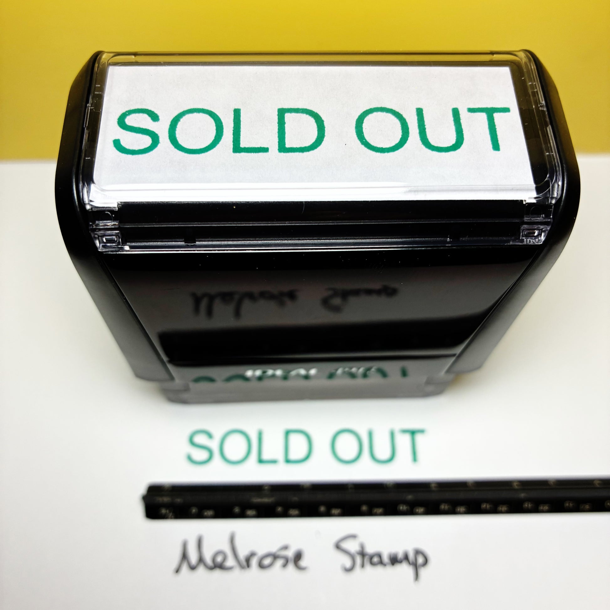 Rubber stamp with 'SOLD OUT' text on a white background, next to a ruler for scale.