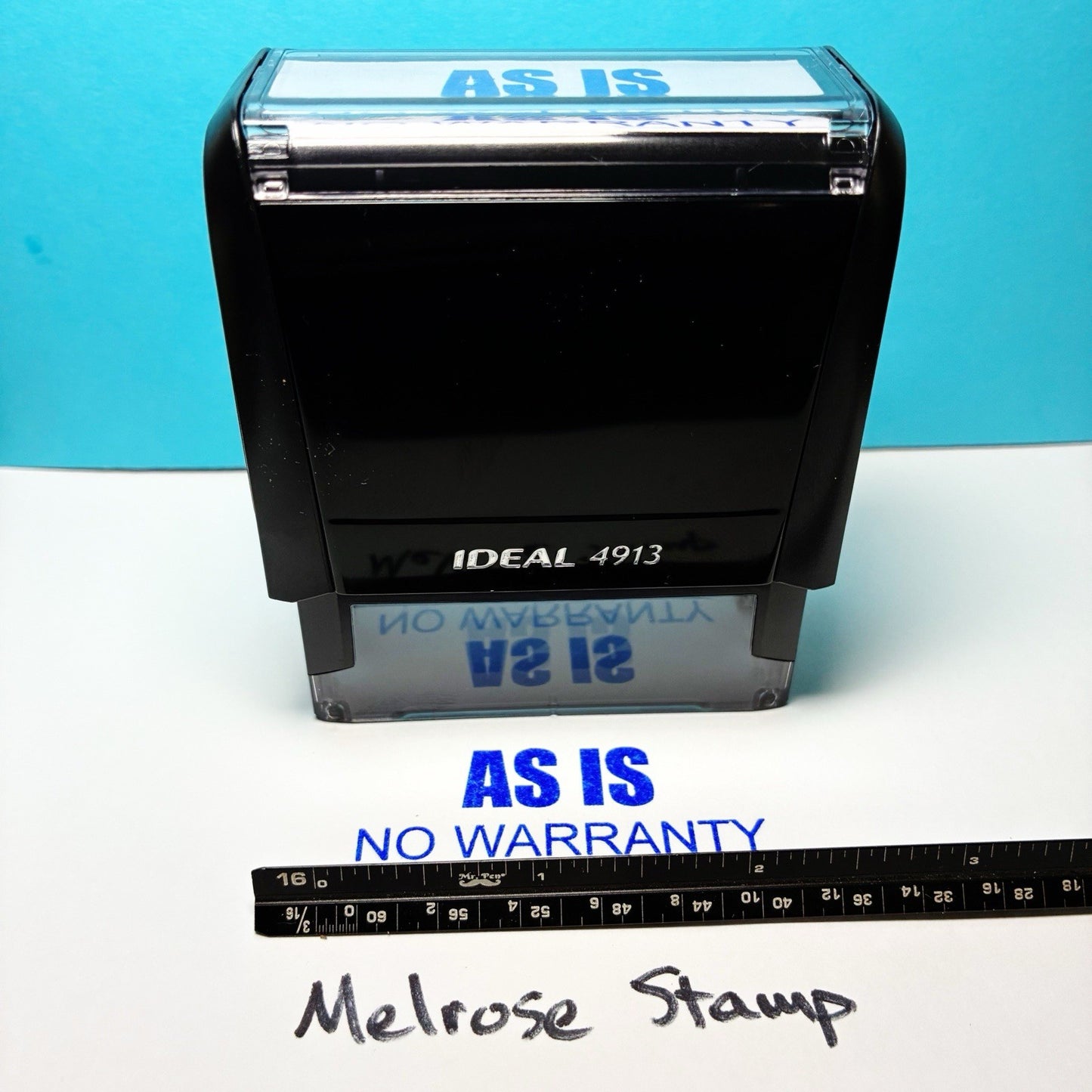 Black stamp with 'AS IS' and 'NO WARRANTY' text on a blue background, with a ruler for scale.