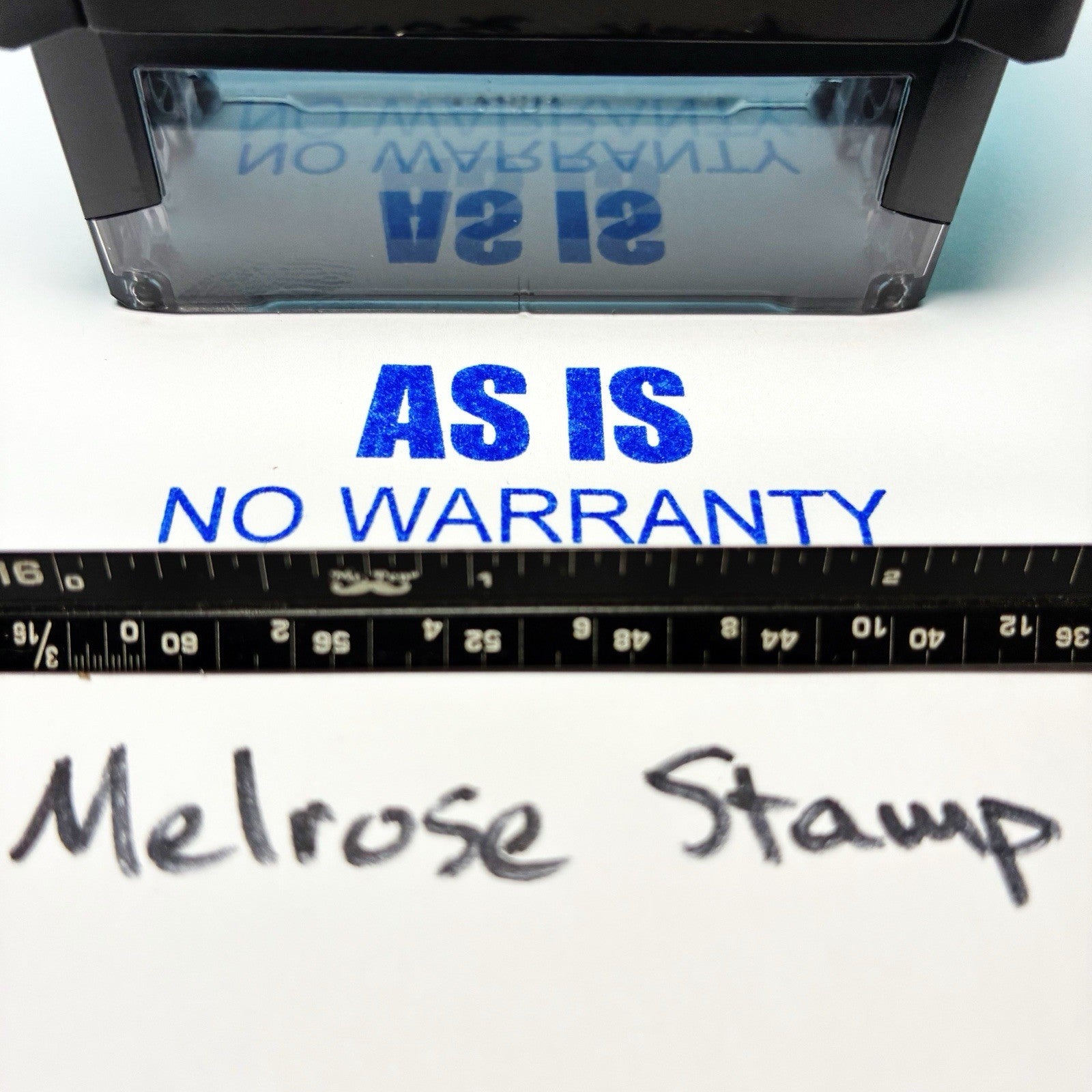 Rubber stamp with 'AS IS NO WARRANTY' text and a ruler for scale on a white background.