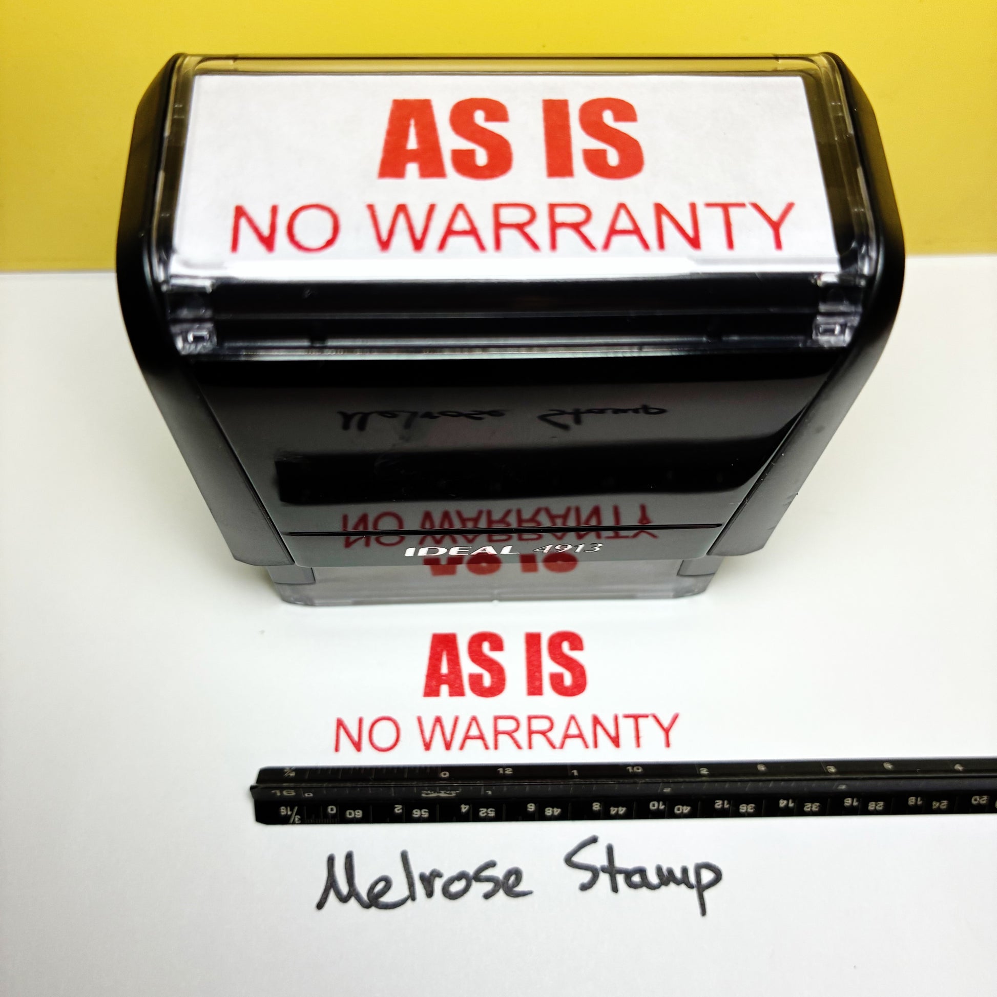 Rubber stamp with 'AS IS NO WARRANTY' text on a white surface with a yellow background.