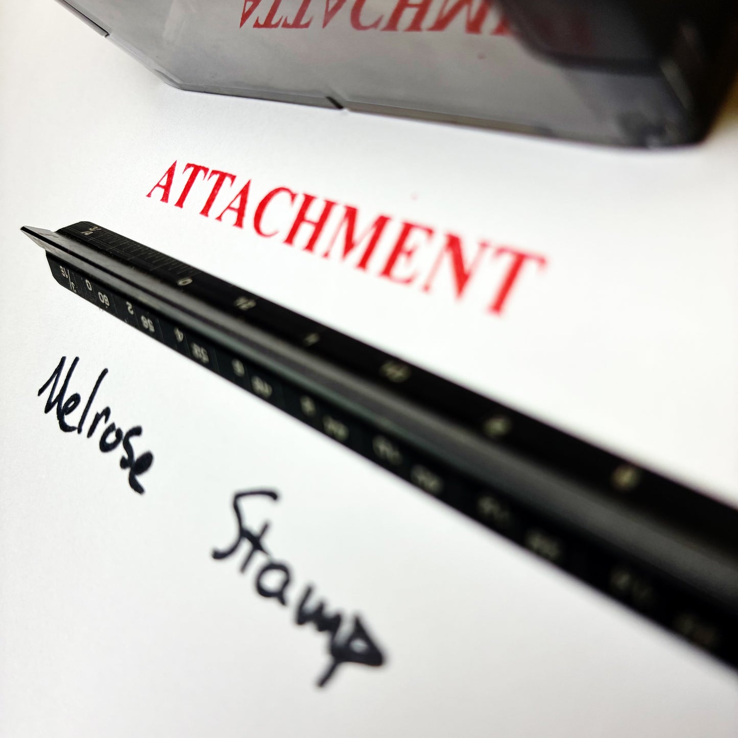 Black stamp with 'Melrose Stamp' text on a white surface, with 'Attachment' in red above.