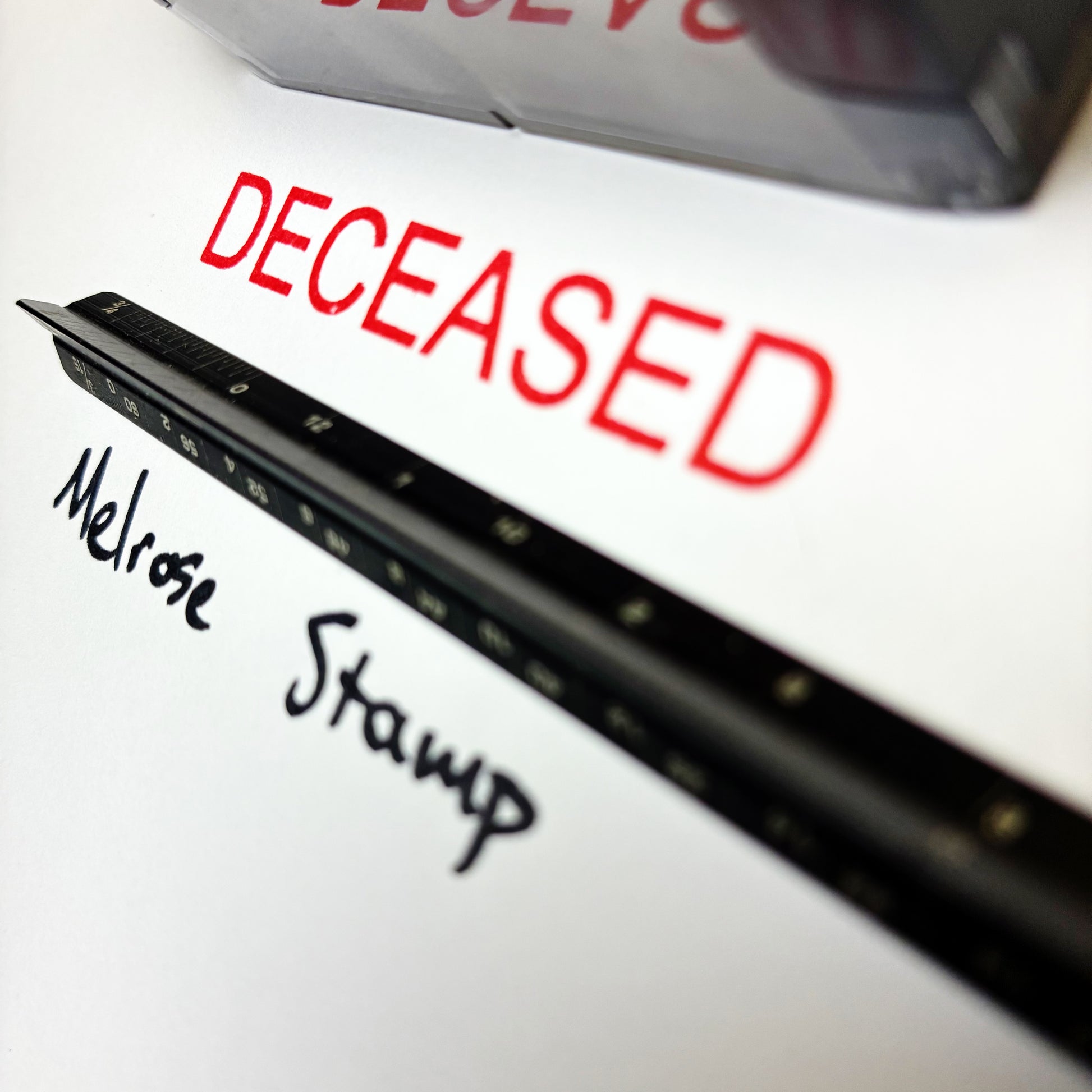 Close-up of a stamp with 'DECEASED' in red and 'Melrose Stamp' in black.