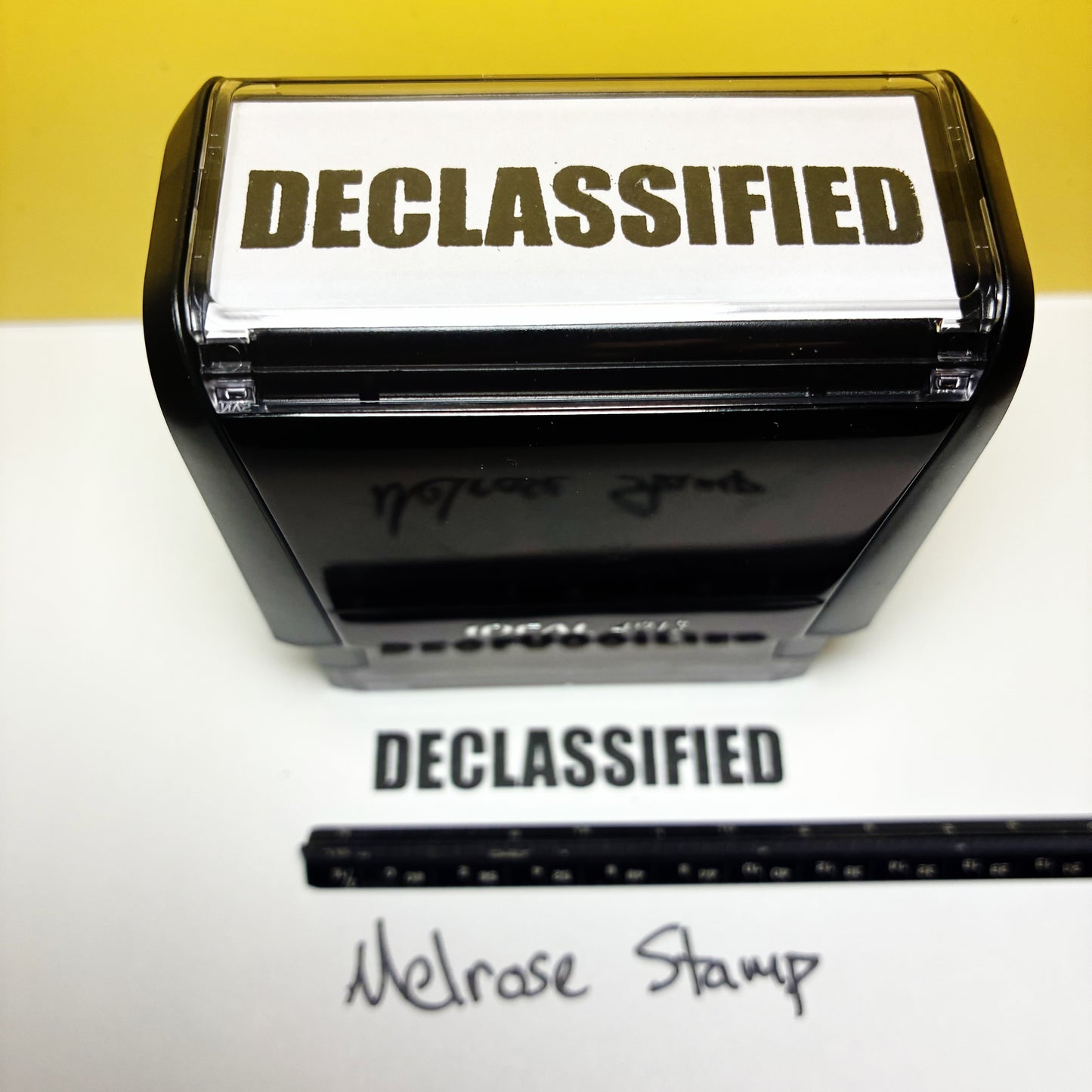 Declassified stamp with a piece of paper showing the text 'DECLASSIFIED' on a white surface.