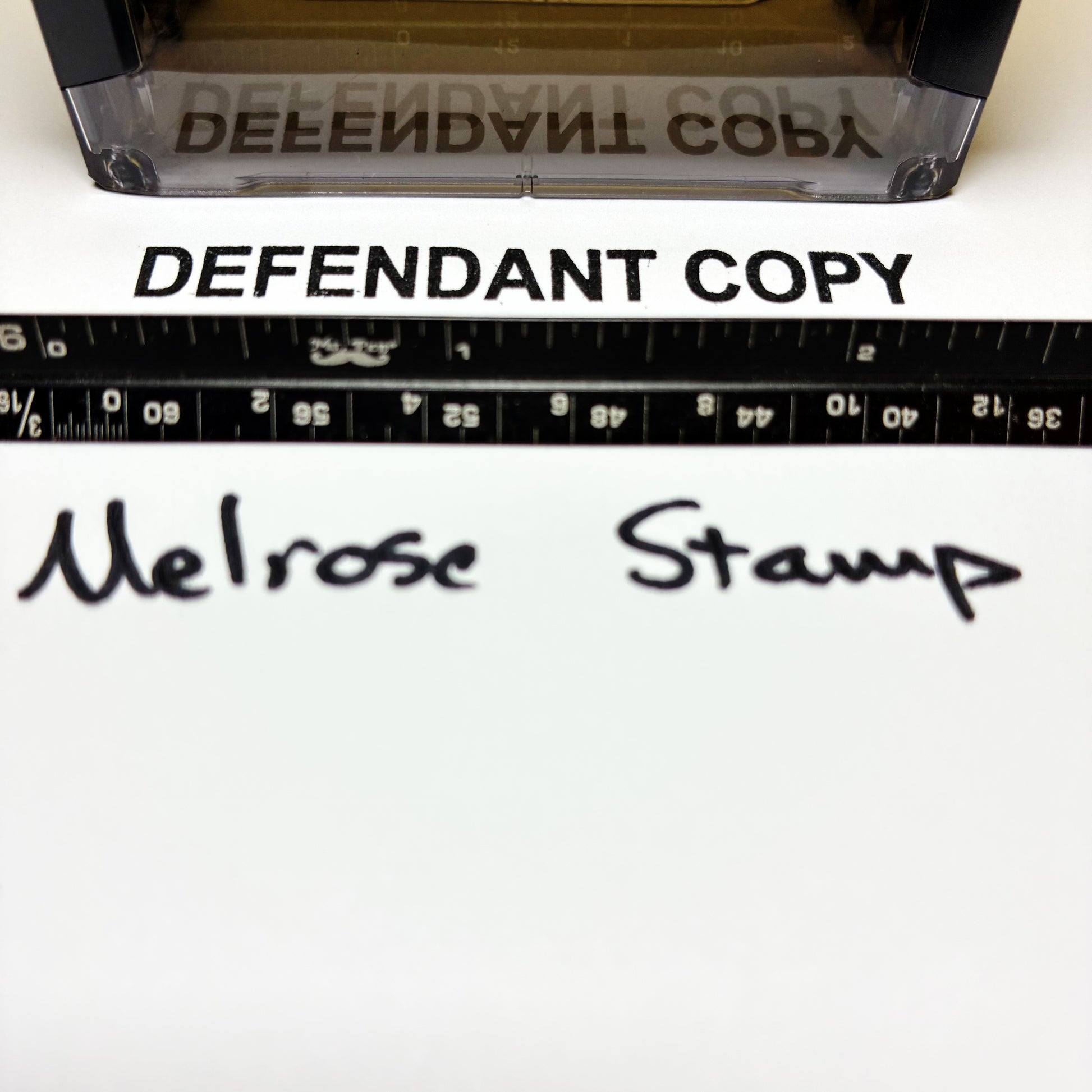 Rubber stamp with 'DEFENDANT COPY' text and a ruler below on a white background.