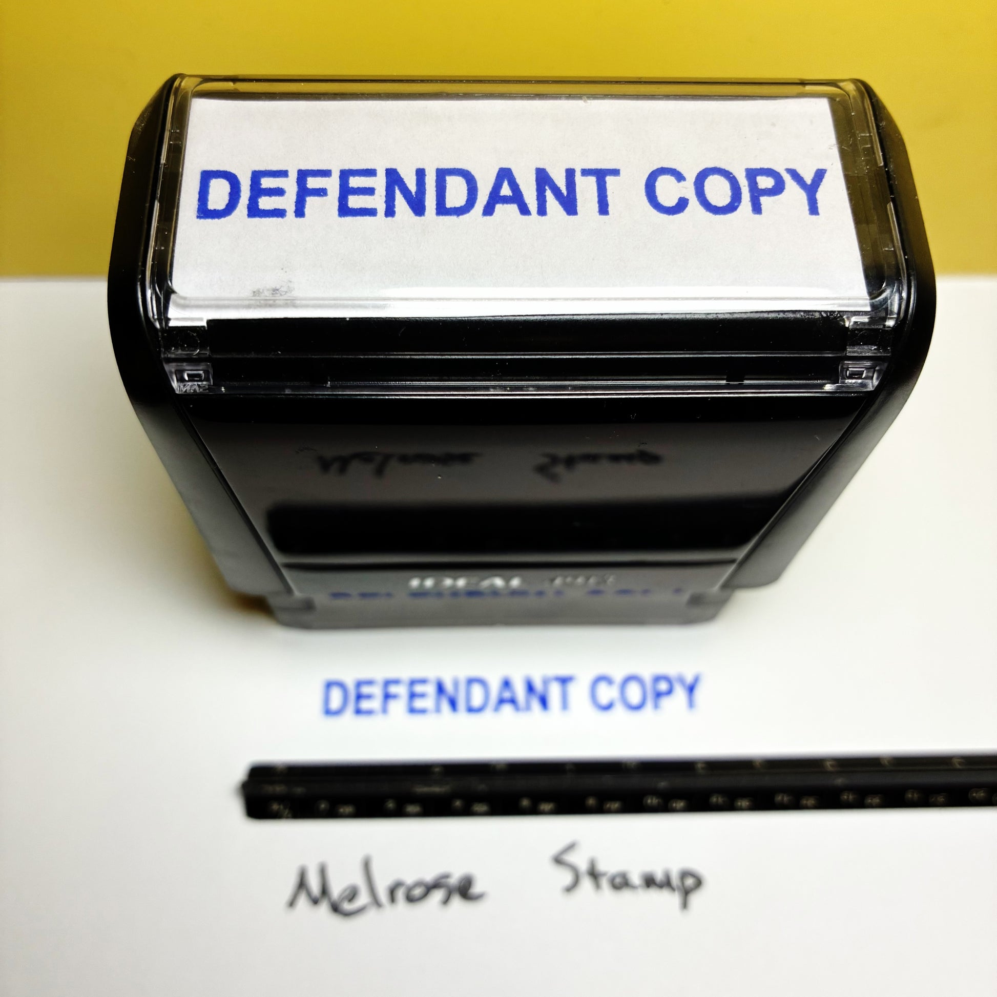 Rubber stamp with 'DEFENDANT COPY' text on a white surface, with a yellow background.