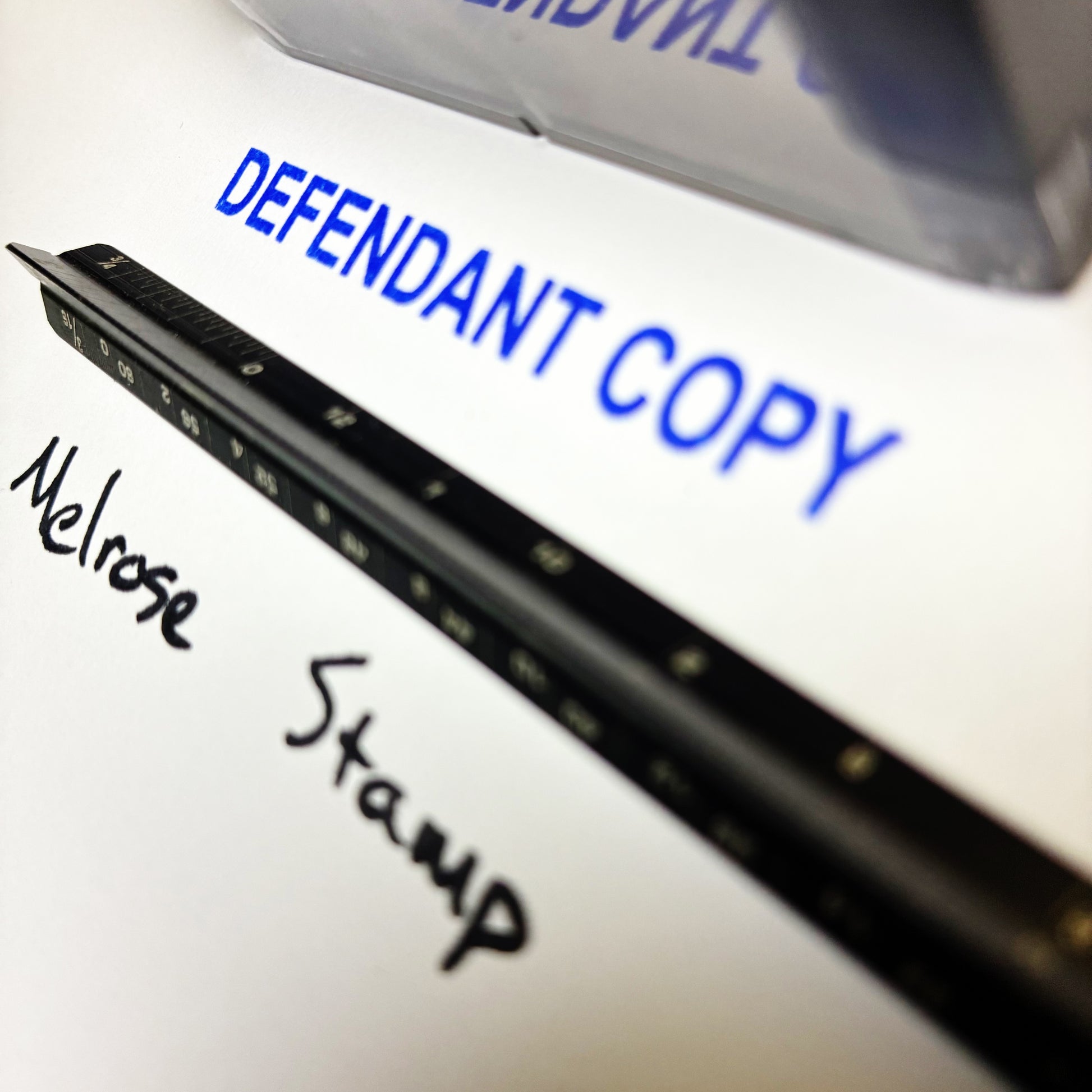 Document with 'DEFENDANT COPY' printed in blue ink, 'Melrose Stamp' handwritten, and a stamp on a white background.