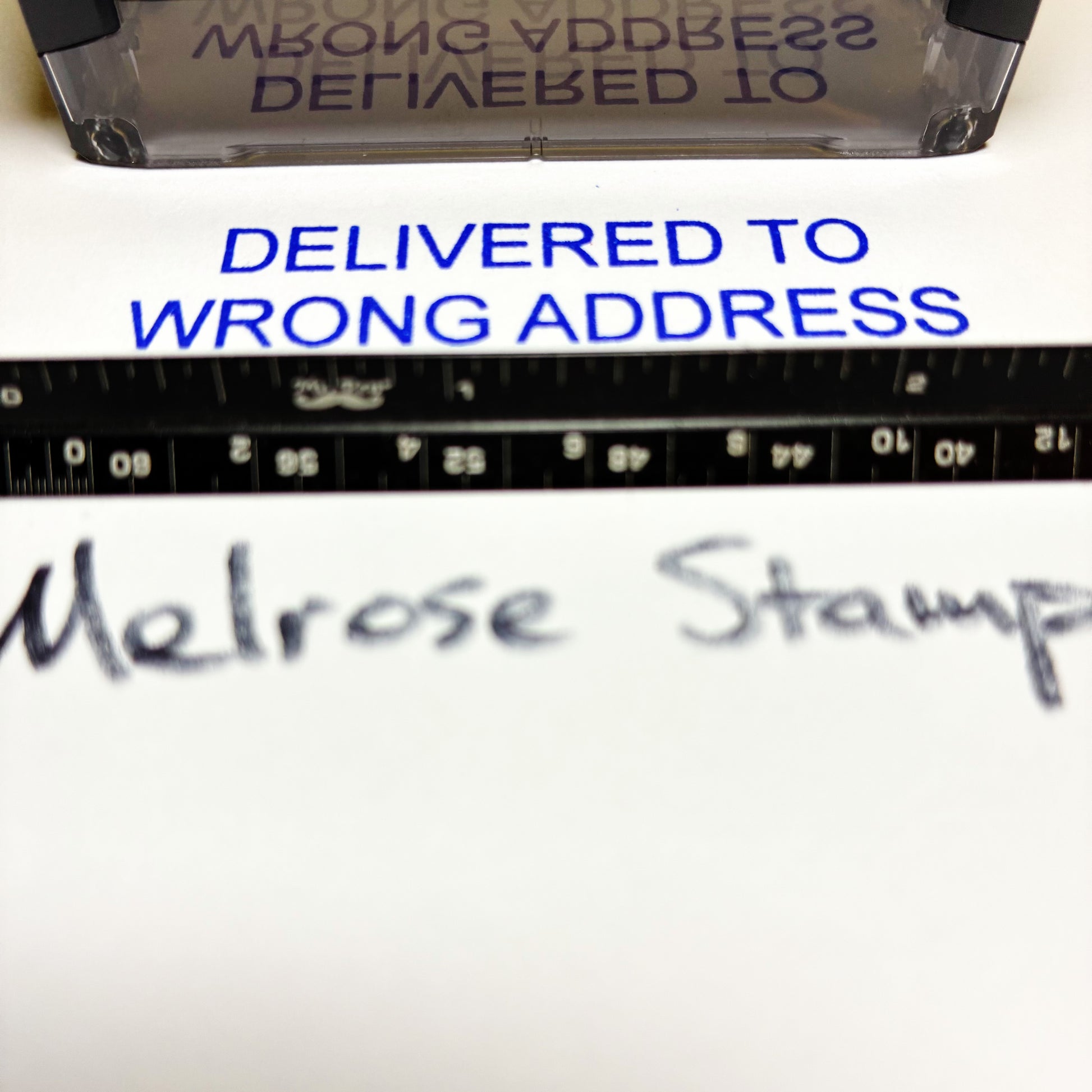Close-up of an impression with 'Delivered to Wrong Address' text and a ruler underneath.