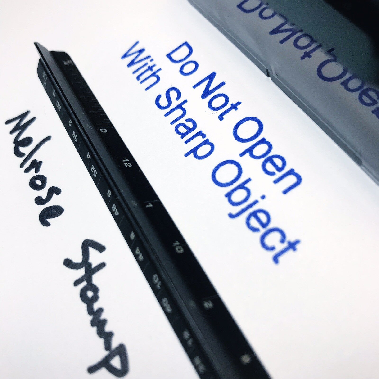 Rubber stamp with text 'Do Not Open With Sharp Object' and 'Melrose Stamp' on a white background