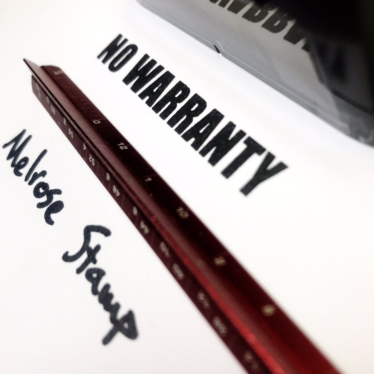 Red ruler with 'Melrose Stamp' branding on a white surface with 'NO WARRANTY' text.