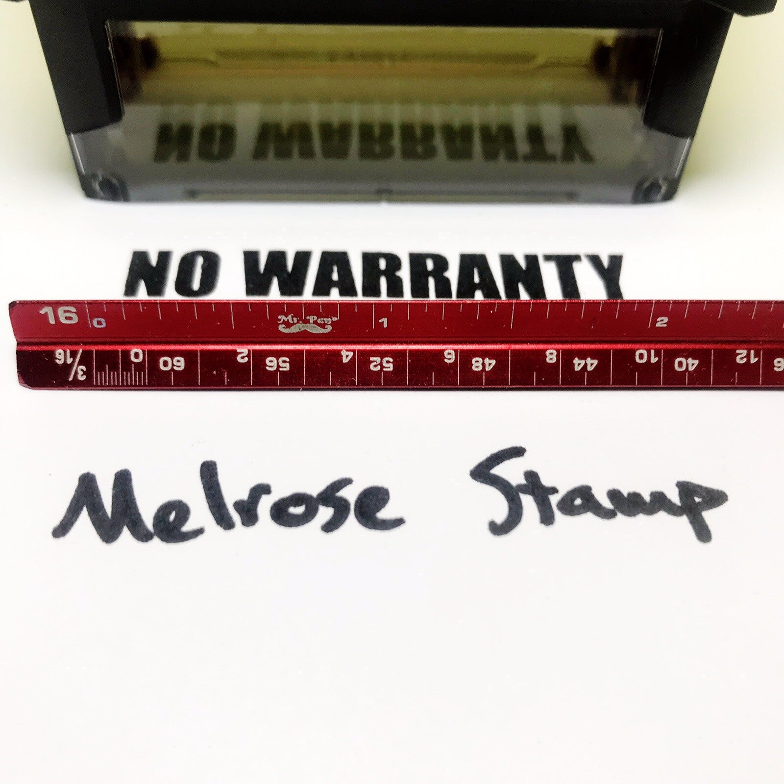 Rubber stamp with 'NO WARRANTY' text and a red ruler for scale on a white background.