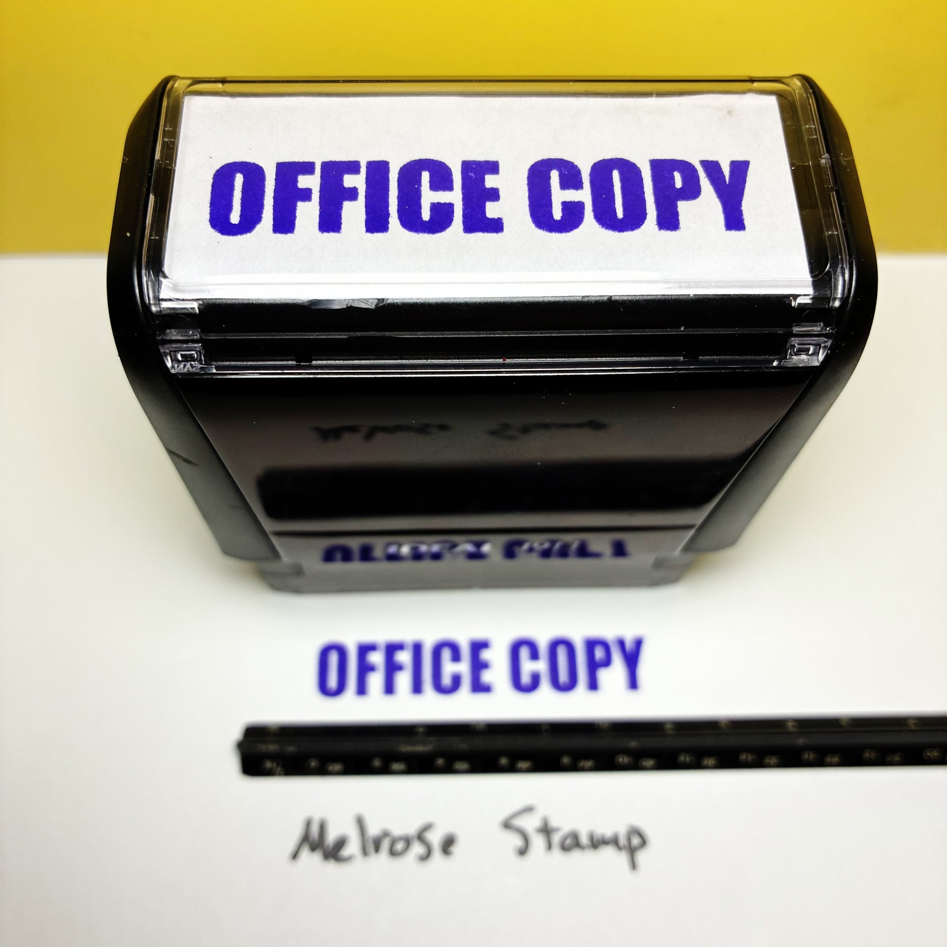 Rubber stamp with 'OFFICE COPY' text on a white surface, with a yellow background.